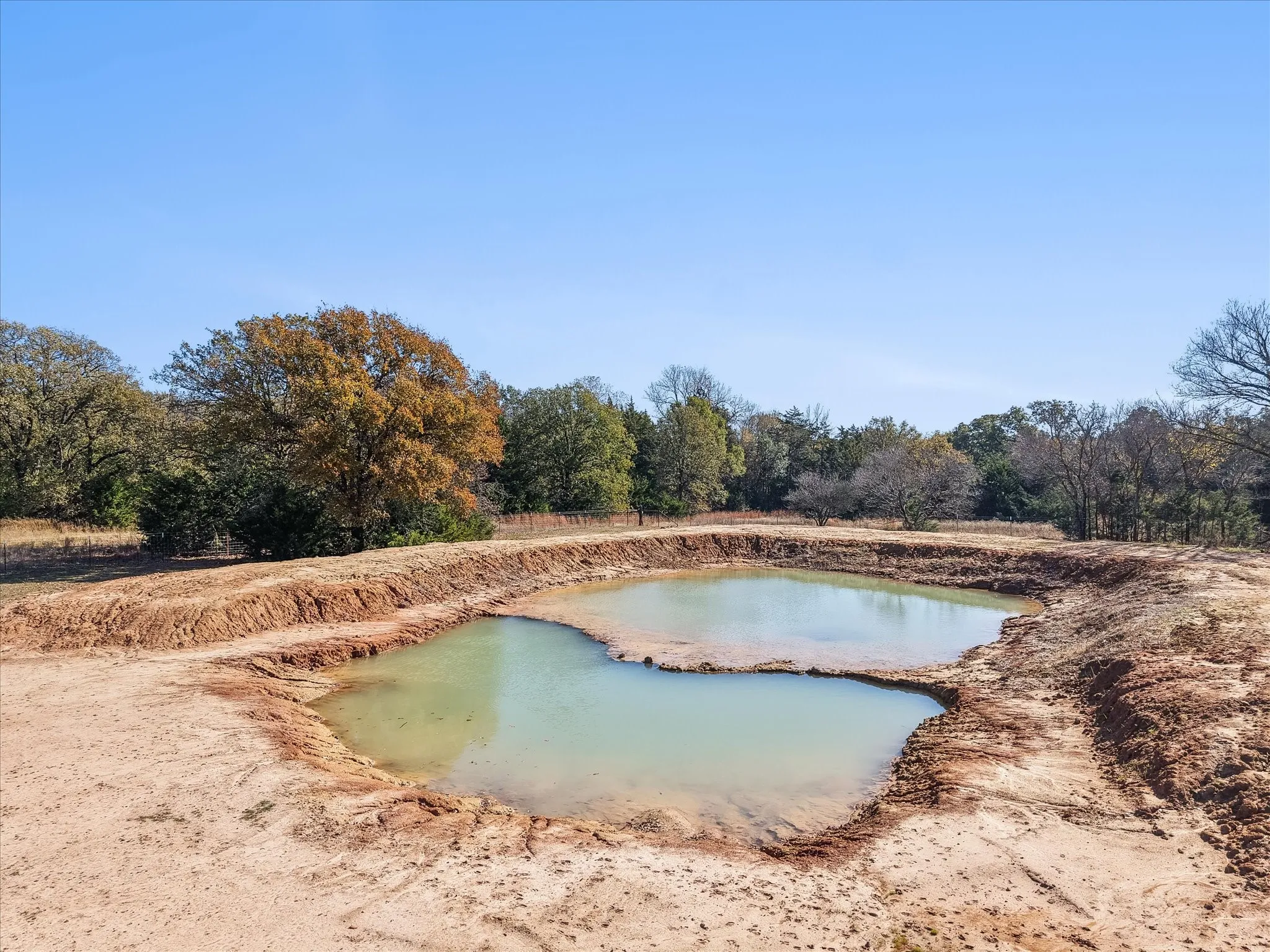 Water feature with surrounding earthen banks and distant deciduous trees