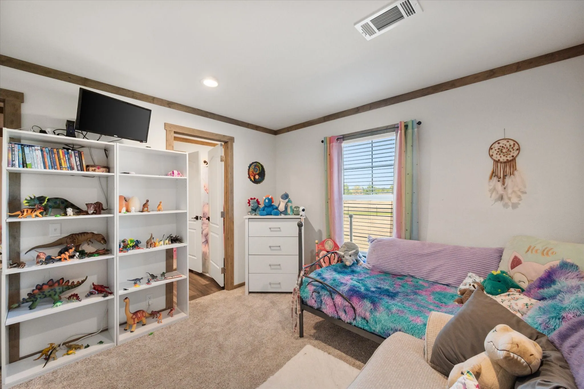 Modern kitchen and dining area featuring a large center island with wood-finish countertop, stainless steel appliances, white cabinetry, pendant lighting, wood-finish flooring, and a dining table with seating for multiple guests