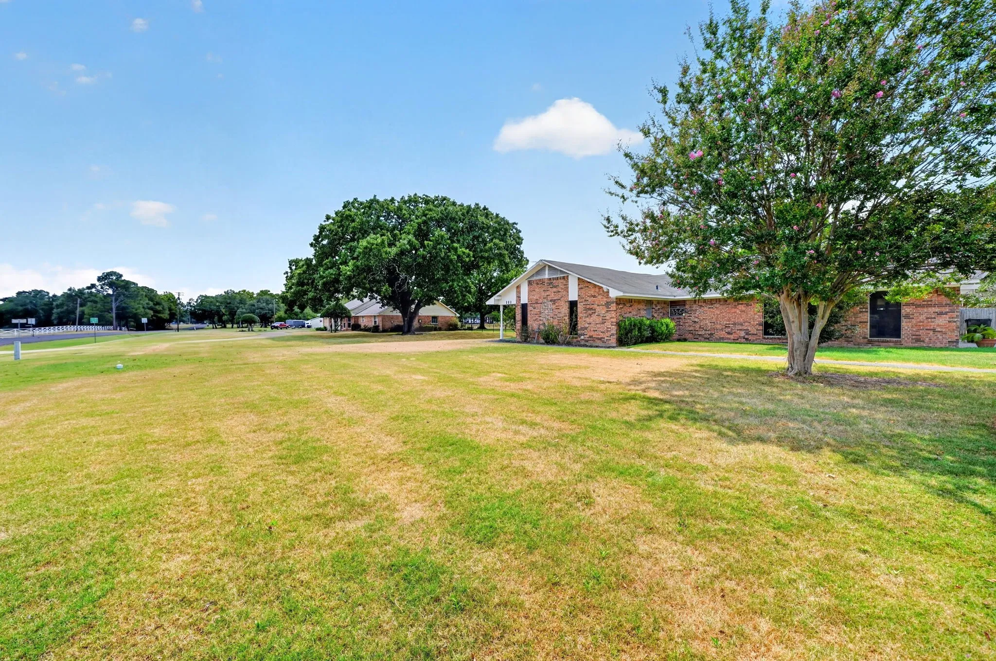 Expansive green space with mature trees, a brick facade building, and a covered entry