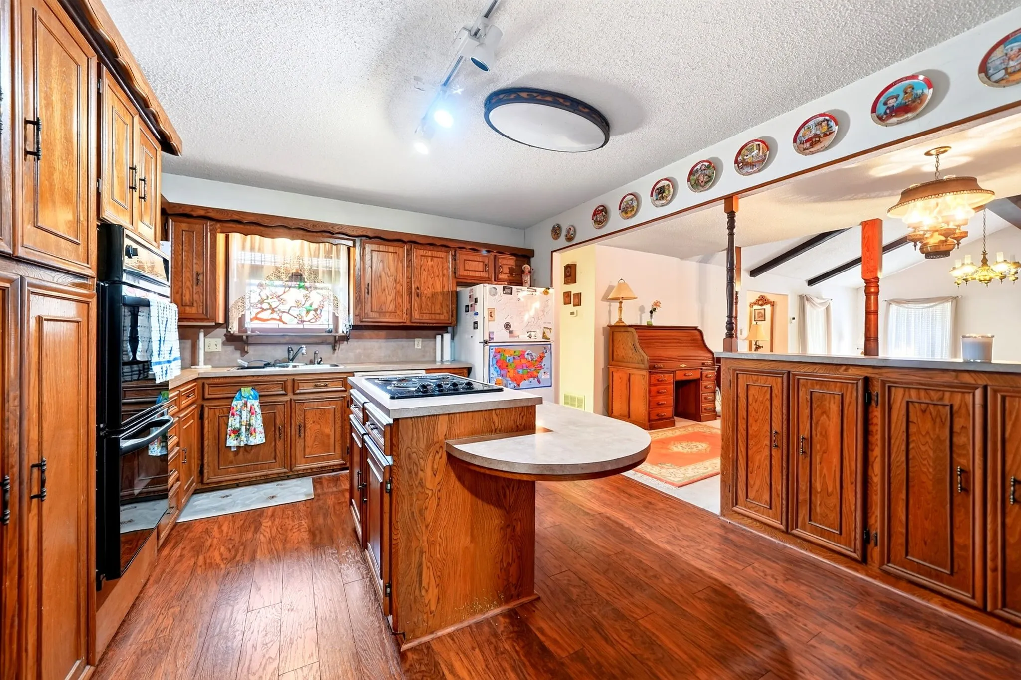 Kitchen featuring wood-finish flooring, wood cabinetry, a built-in oven, and a center island with a cooktop