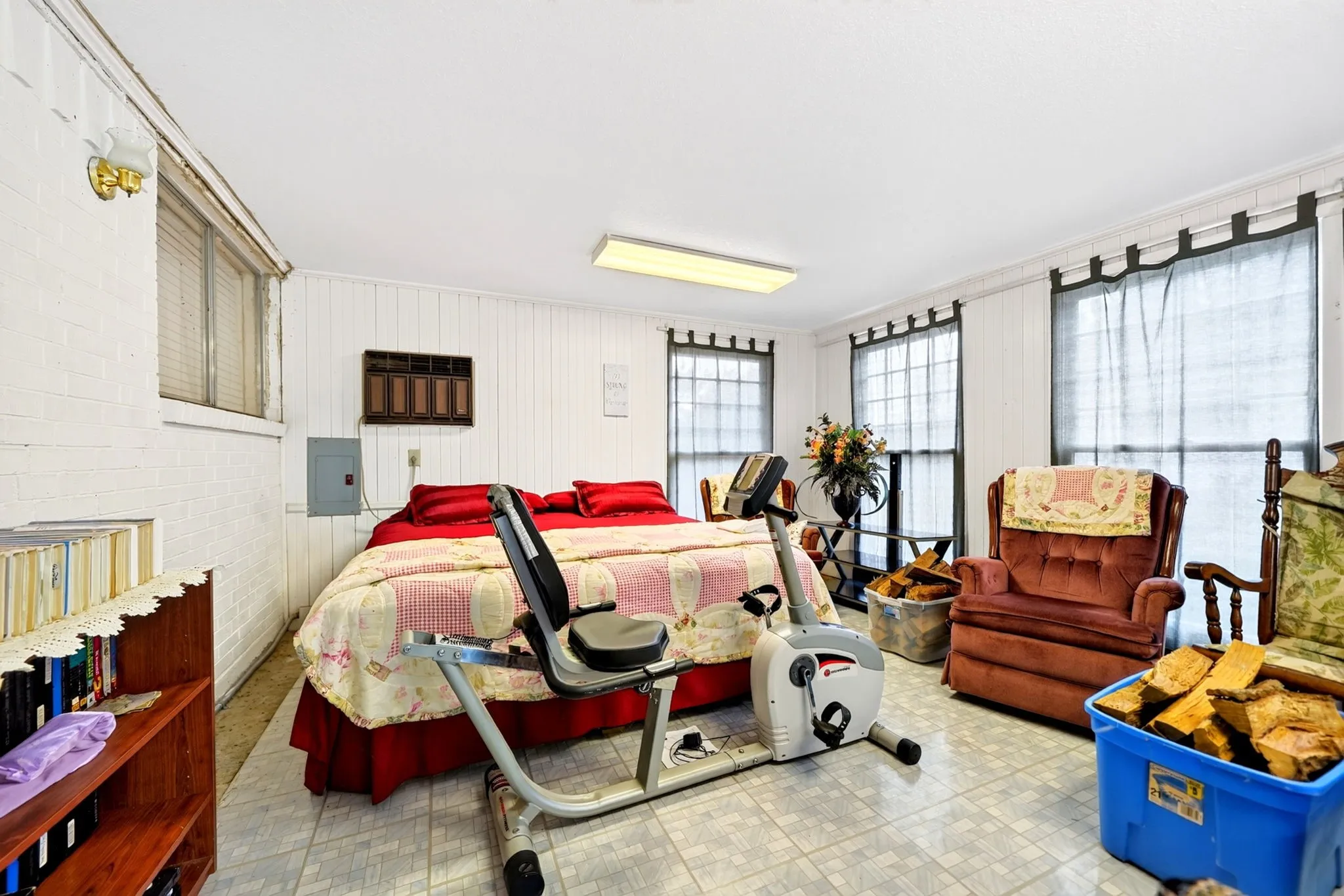 Room featuring white paneled walls, multiple windows with blinds, and light-colored tile flooring