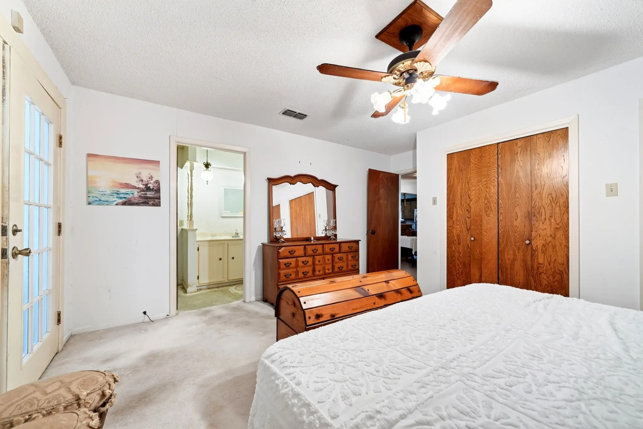 Ceiling fan light fixture, wood-finish bi-fold closet doors, wall-to-wall carpeting, and French door with transom windows
