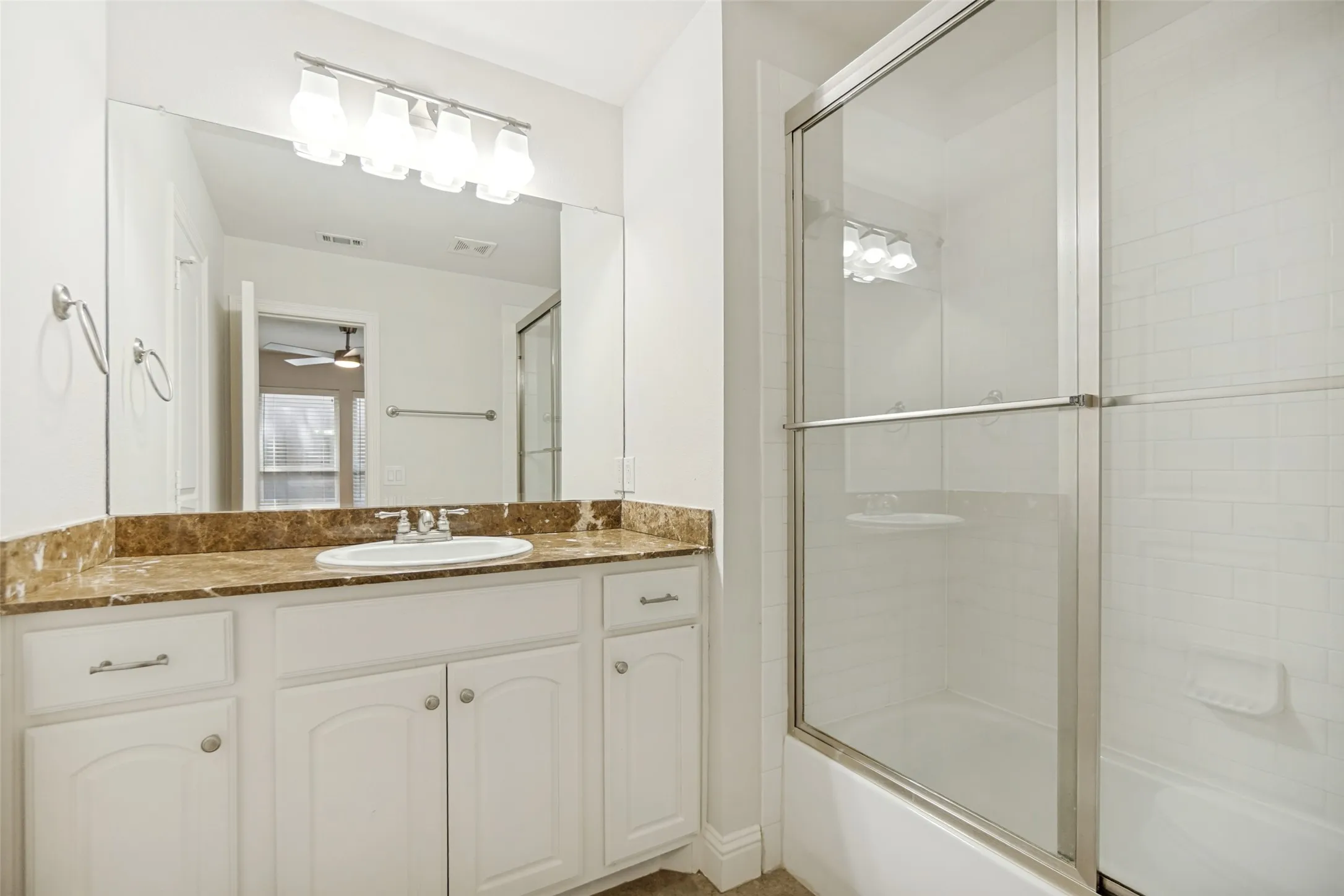 White vanity with ample storage, integrated basin, and a brown marble-look countertop