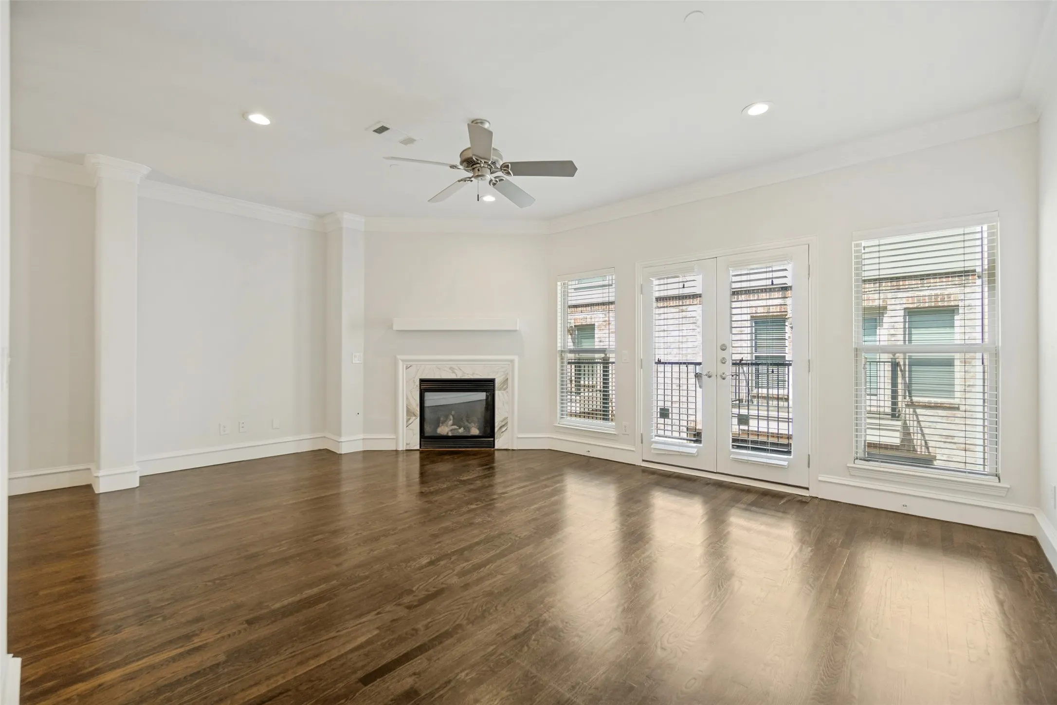 Hardwood flooring, crown molding, a fireplace with a stone surround, recessed lighting, and a ceiling fan