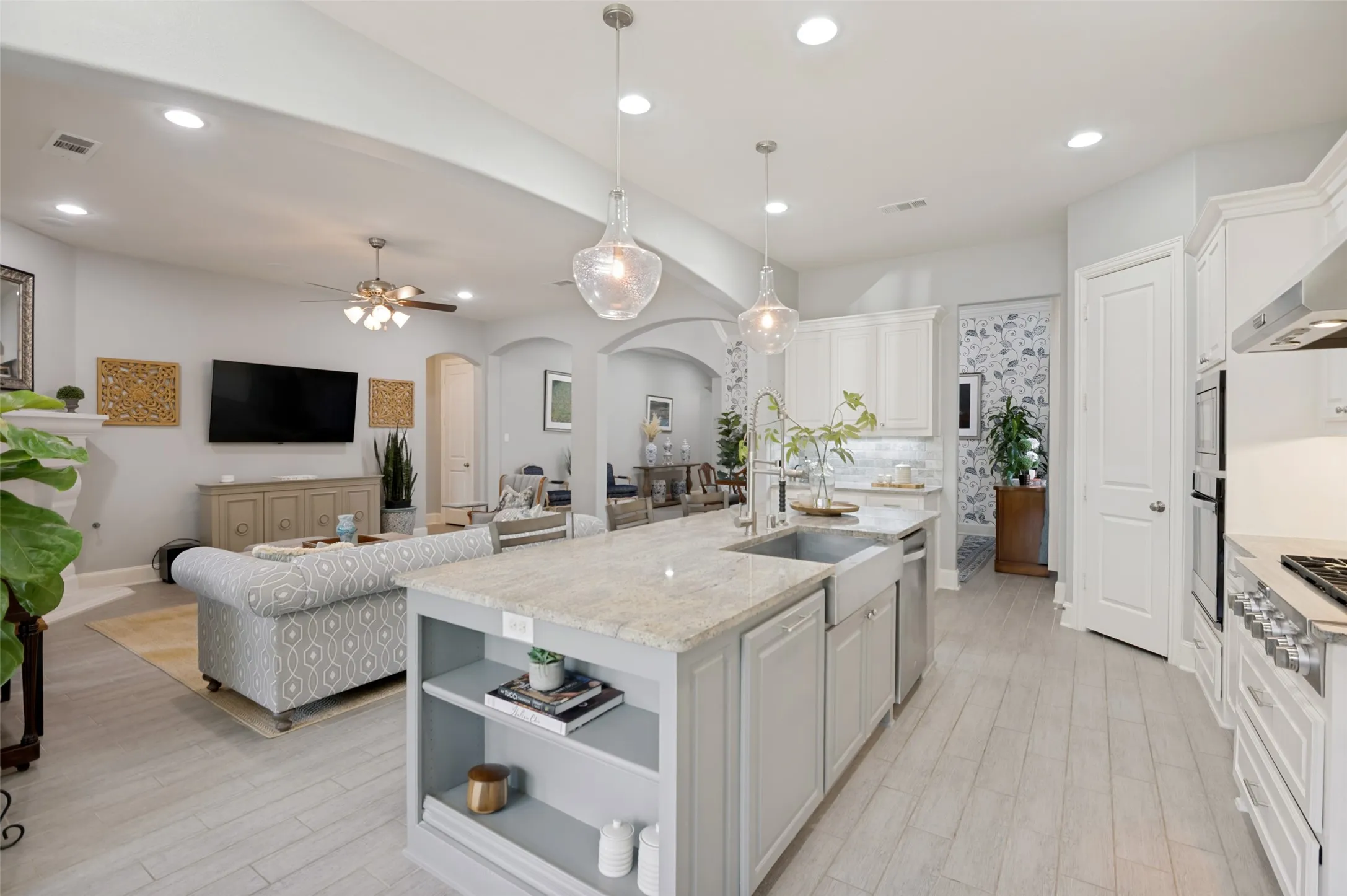 The heart of the home features a chef-inspired kitchen with a large quartz island, farmhouse sink,  oven, gas cooktop, and abundant cabinetry, all seamlessly flowing into the spacious family room—creating the perfect space for everyday living and entertaining.