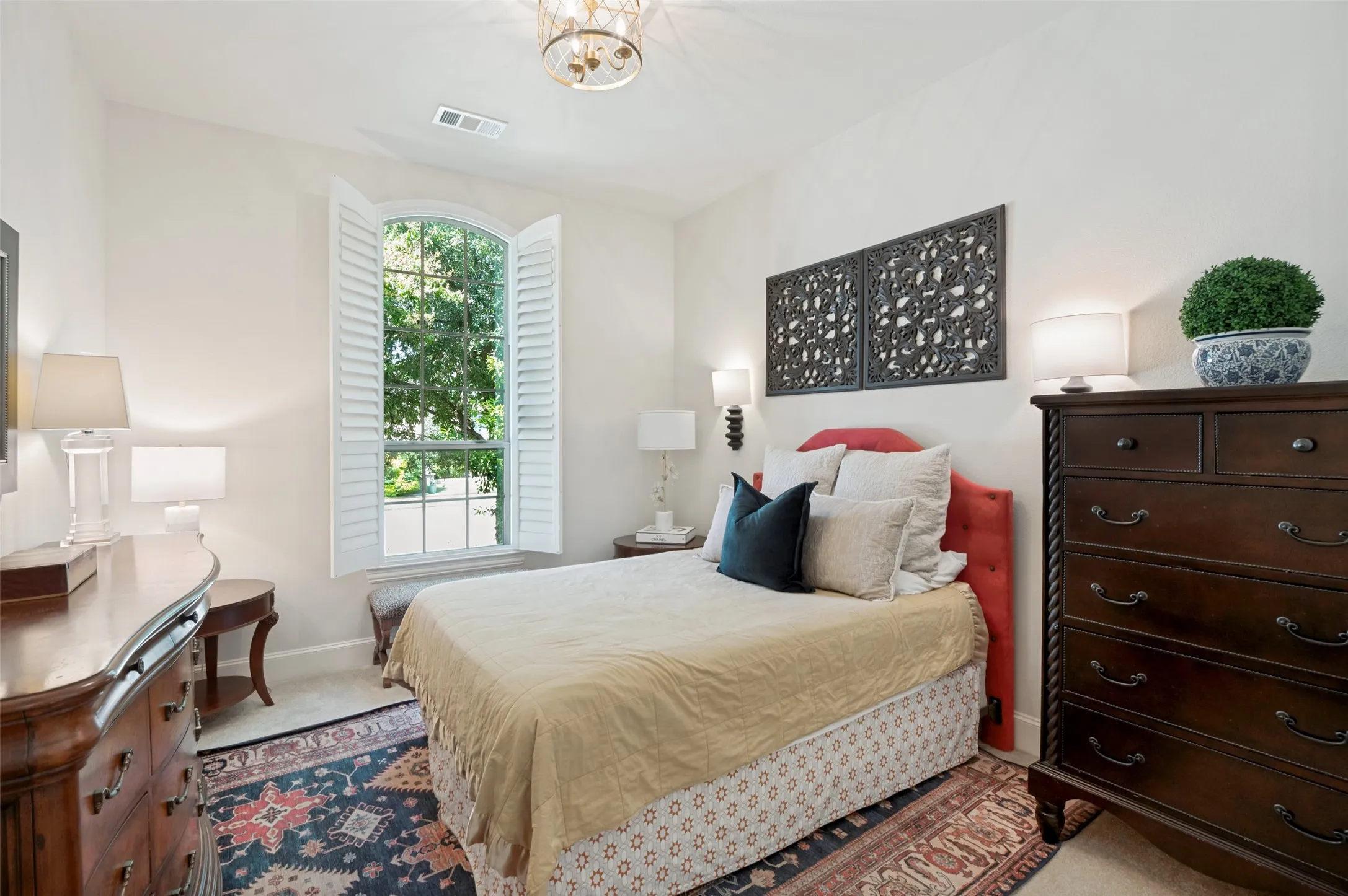 nviting secondary bedroom featuring a large arched window with plantation shutters, abundant natural light, and a spacious layout—perfect for family, guests, or a private retreat.