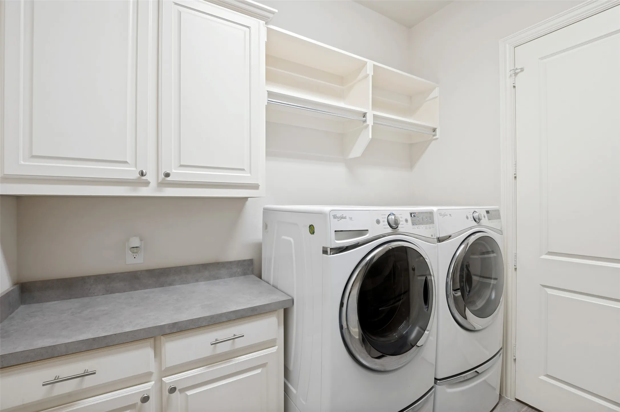 Spacious laundry room with built-in cabinetry, folding counter, and ample storage, making everyday chores convenient and organized.