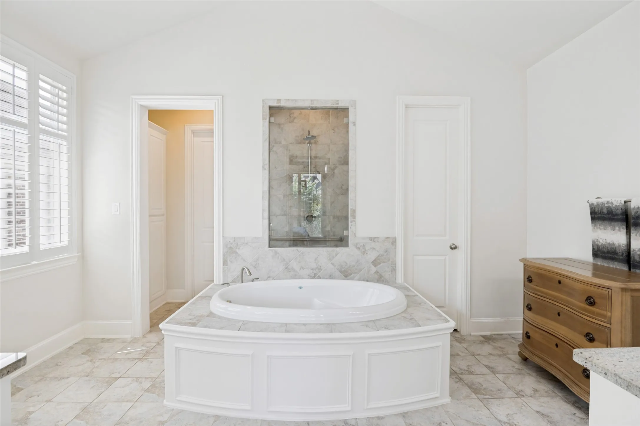 Relax and unwind in the spa-inspired primary bath featuring a soaking tub, abundant natural light, and a serene atmosphere—perfect for everyday luxury.