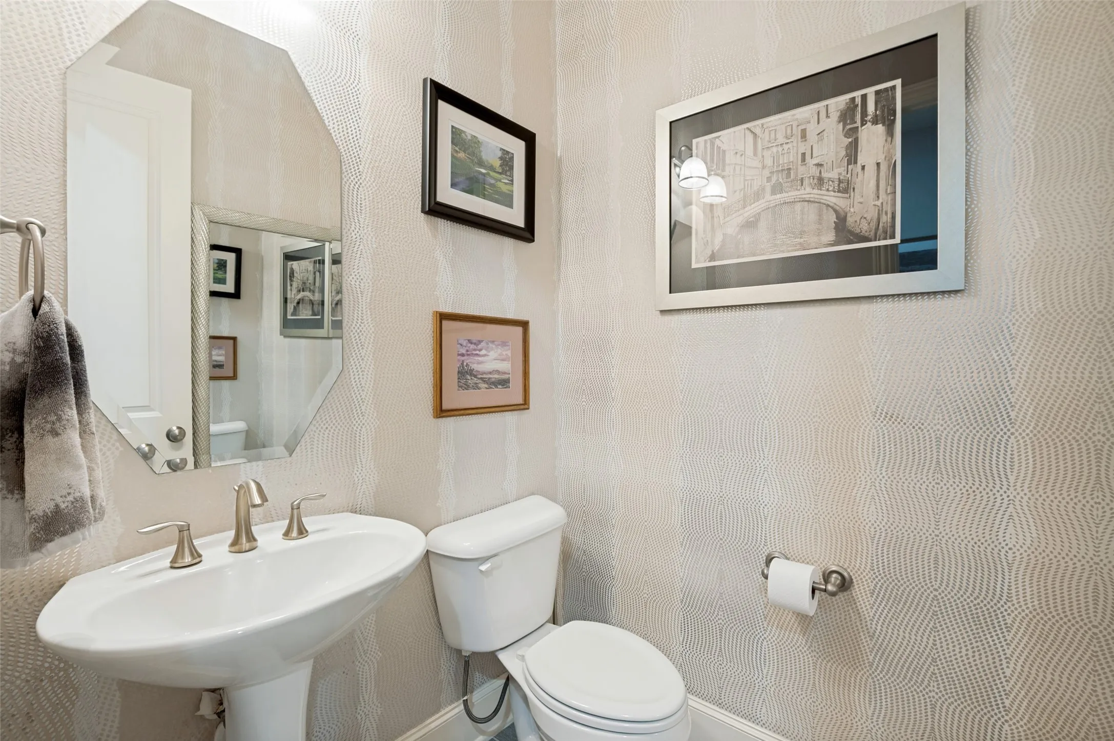 Stylish powder bath featuring designer wallpaper, pedestal sink, and elegant finishes, providing a sophisticated touch for family and guests.