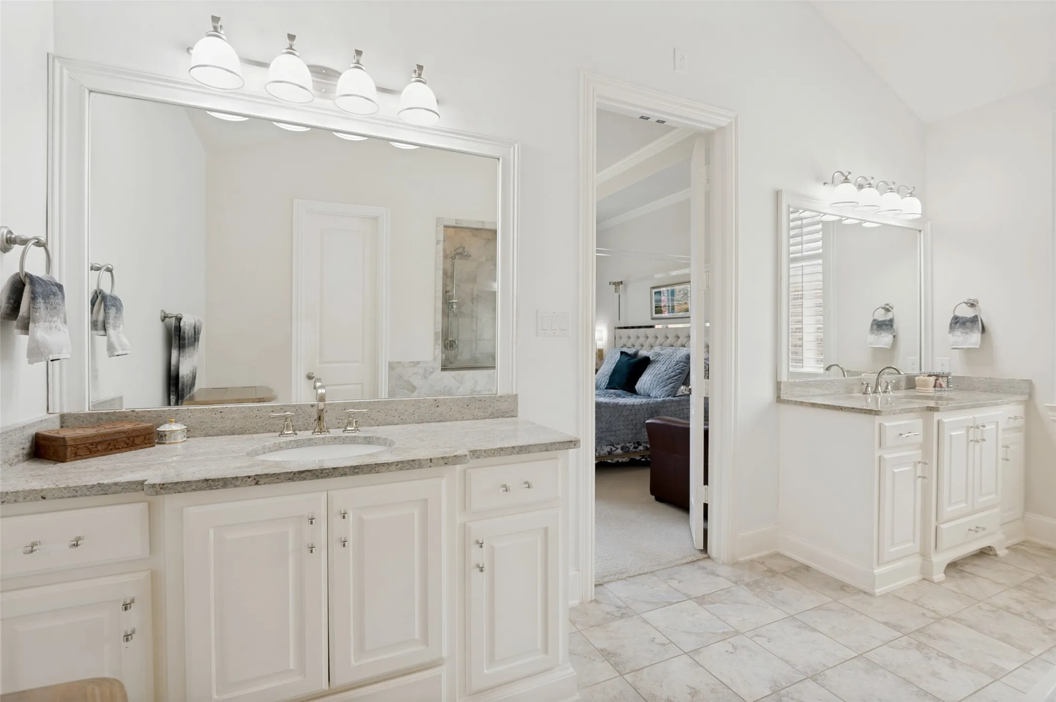 Elegant primary bath with separate dual vanities, granite countertops, and abundant storage, offering convenience and privacy in a bright, spacious setting.