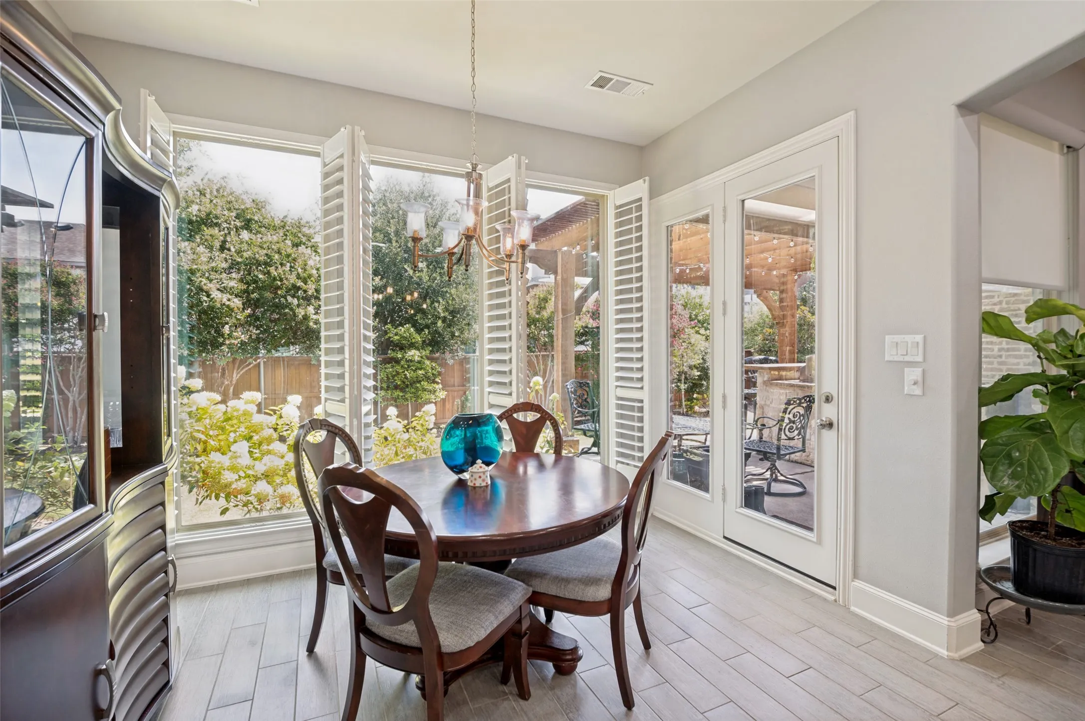 Light-filled breakfast room surrounded by oversized windows with plantation shutters, offering beautiful views of the landscaped backyard and seamless access to the covered patio—perfect for casual dining and indoor-outdoor entertaining.