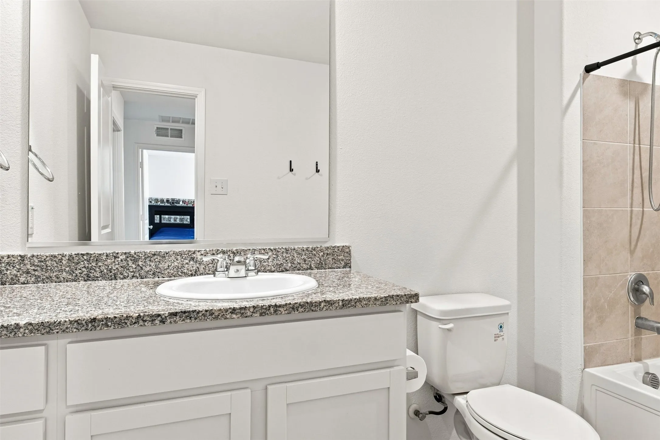 White vanity with shaker-style cabinetry, granite-finish countertop, and undermount sink