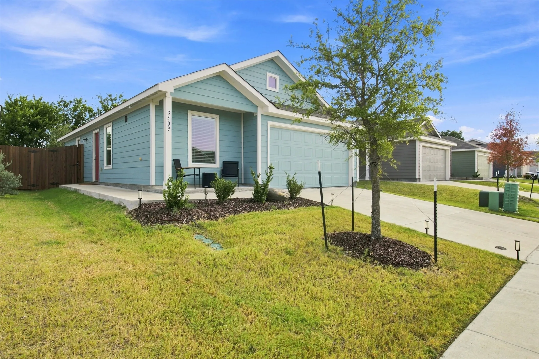 Single-story residence featuring light blue siding, an attached garage, a concrete driveway, and a fenced side yard
