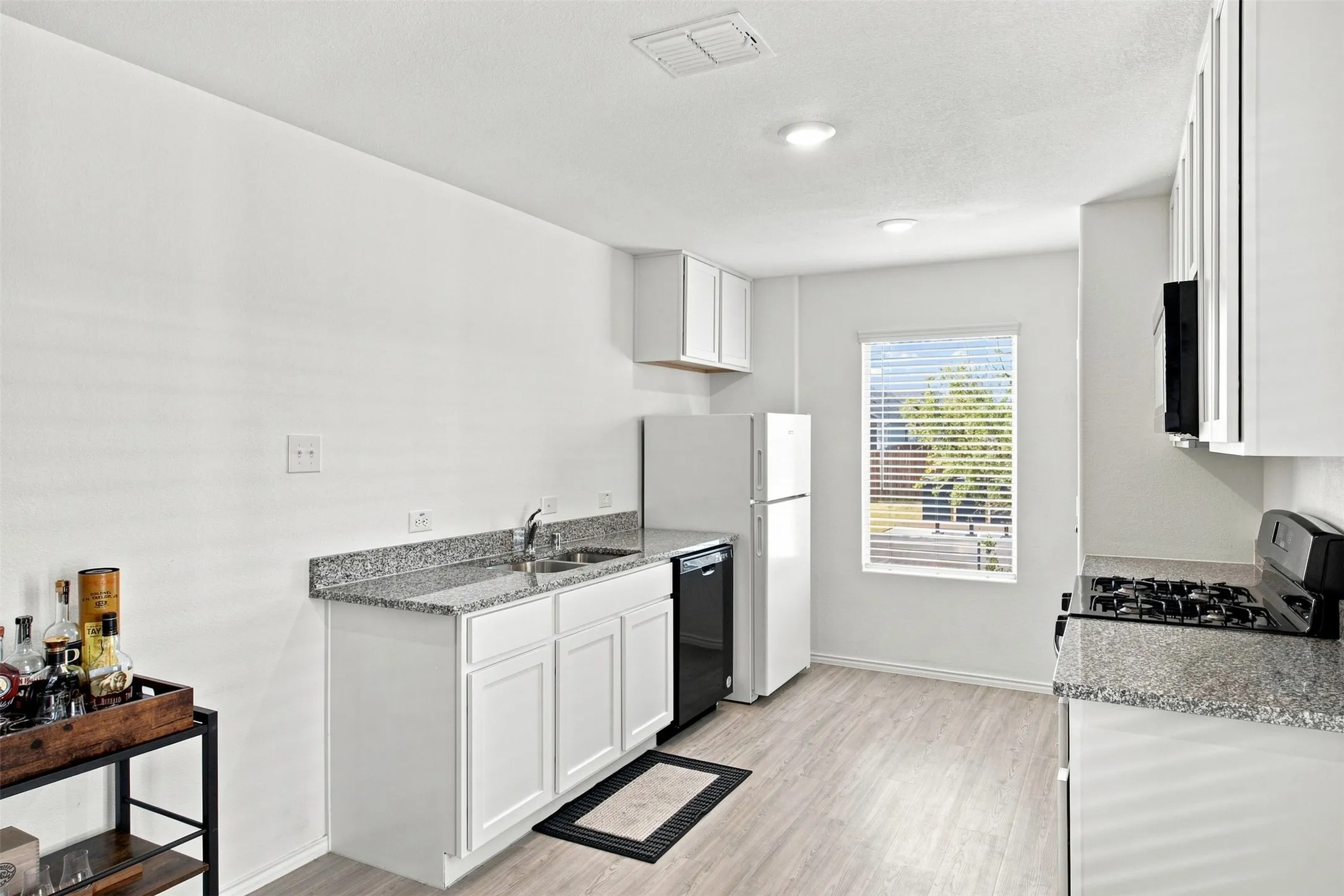Kitchen featuring white cabinetry, granite-style countertops, wood-finish flooring, and recessed lighting