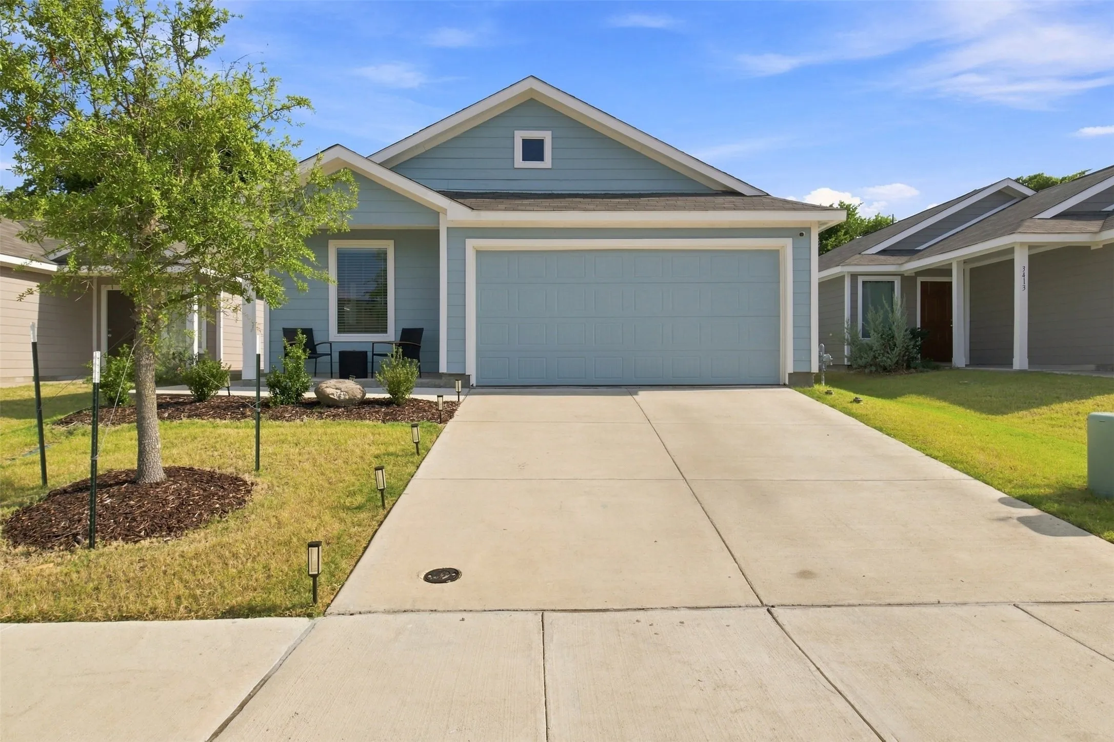 Single-story residence featuring light blue siding, an attached two-car garage, and a concrete driveway