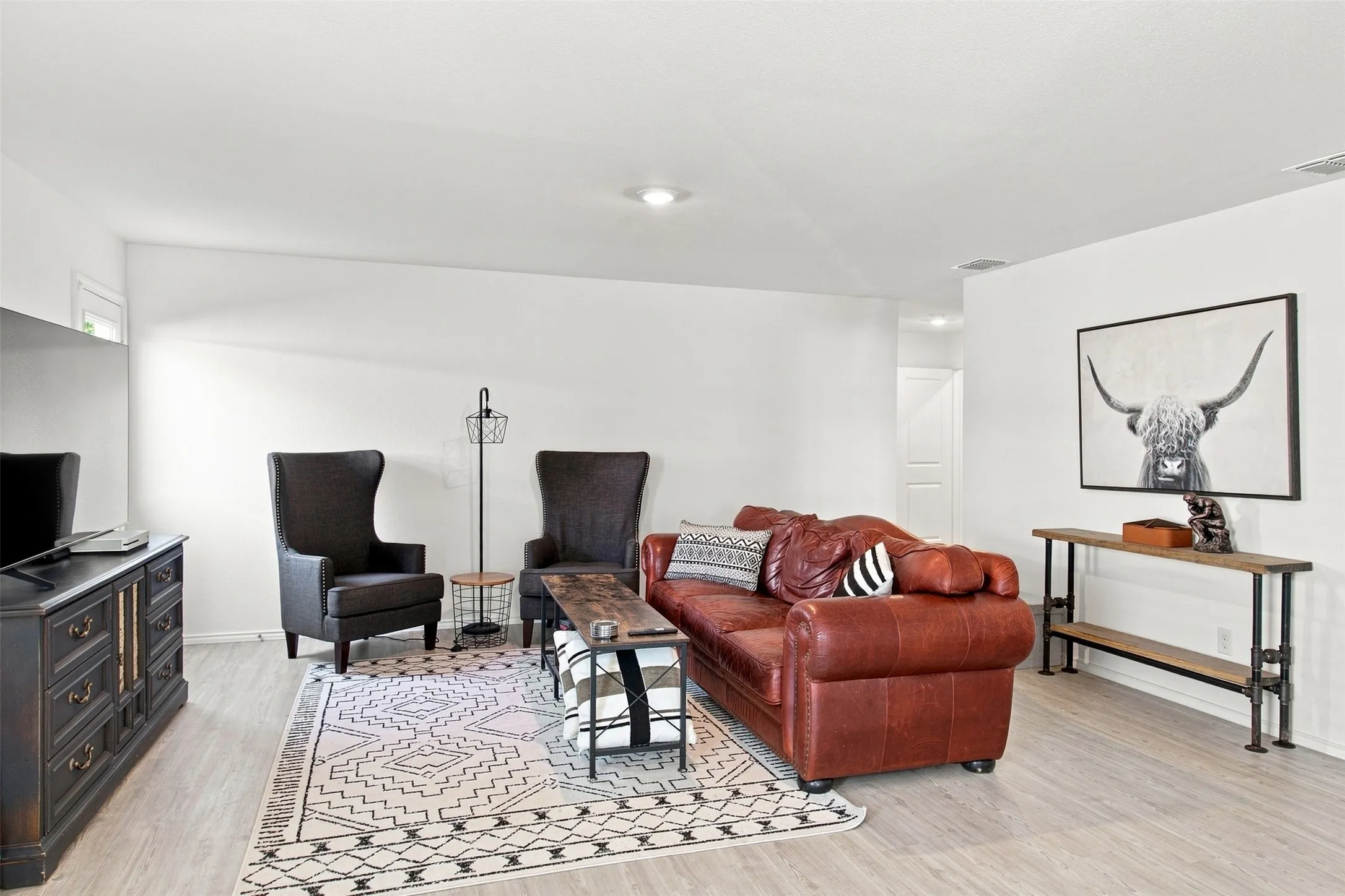 Recessed lighting illuminates the open living space, featuring light wood-finish flooring
