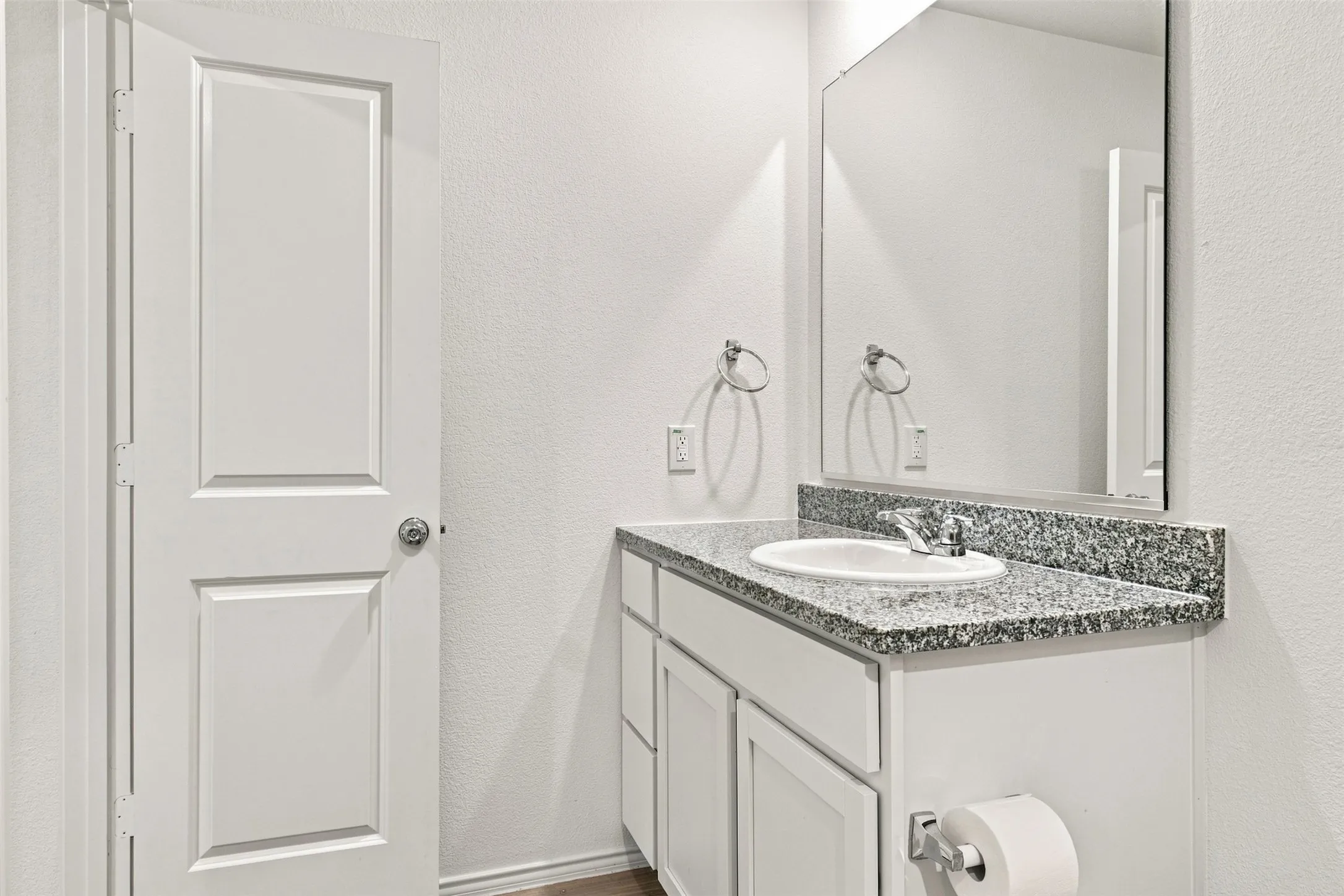 Vanity with an integrated sink, granite countertop, chrome faucet, and storage cabinetry