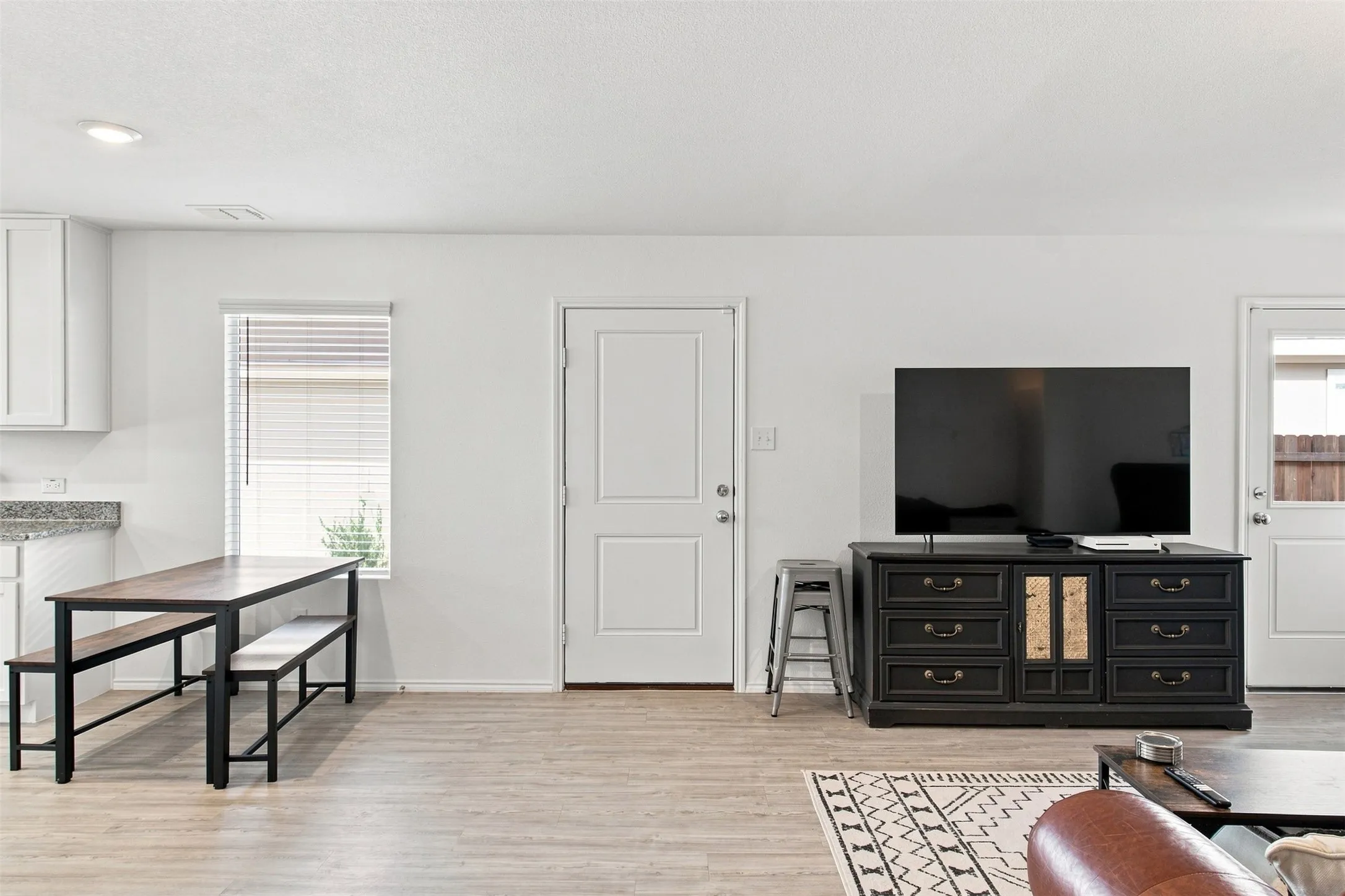 Recessed ceiling lighting, wood-finish flooring, white paneled doors, and a built-in kitchen counter with a light-toned surface