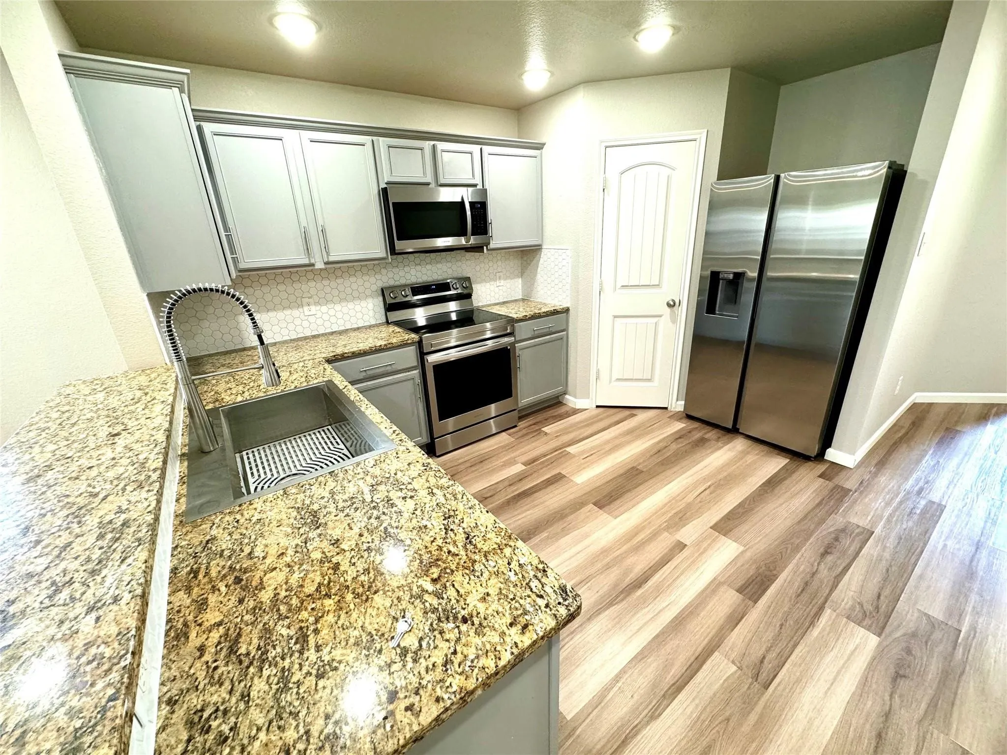 Modern kitchen featuring stainless steel appliances, including a side-by-side refrigerator, electric range, and microwave