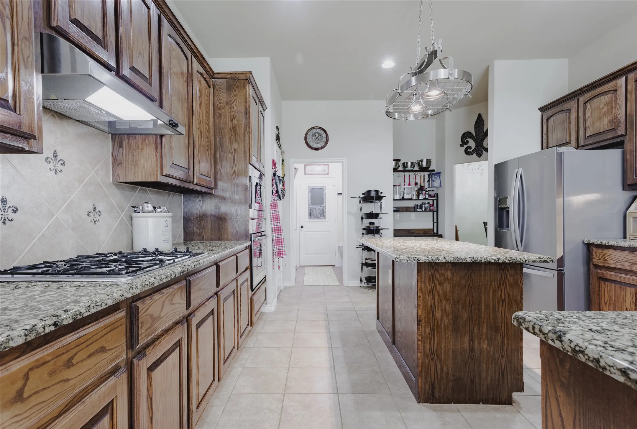 Kitchen featuring wood-finish cabinetry, granite countertops, stainless steel appliances, and a gas cooktop
