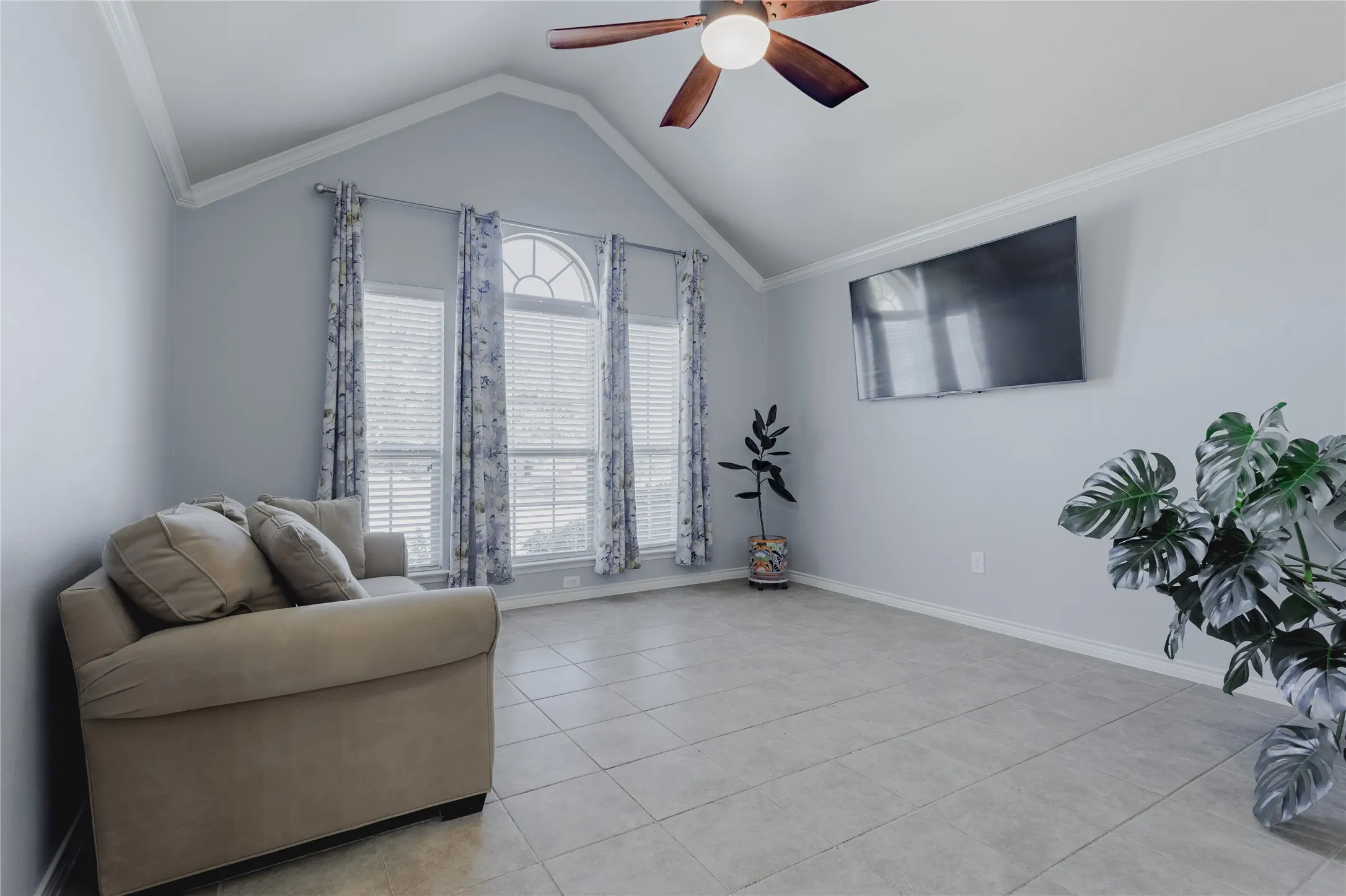 Bright, open living space featuring vaulted ceilings, tile flooring, and abundant natural light from French doors with transom windows