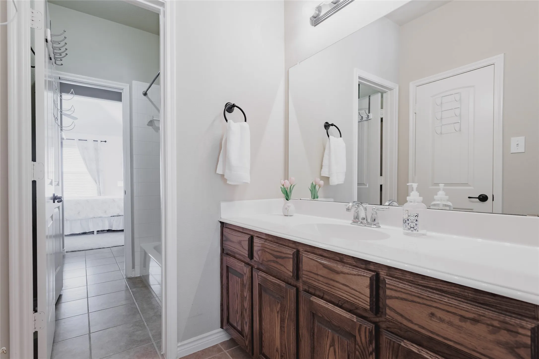 Bathroom showcasing a wood-finish vanity with dual sinks, white quartz countertop, and polished chrome fixtures