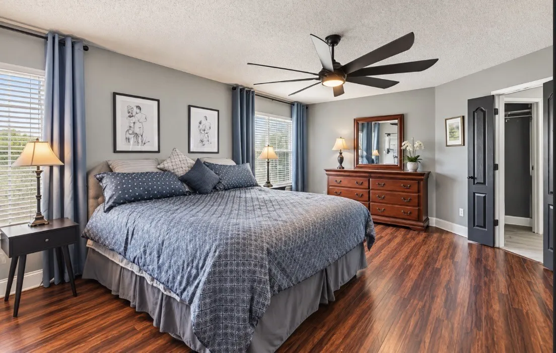 Wood-finish flooring, ceiling fan with integrated lighting, multiple windows, and a built-in closet with double doors