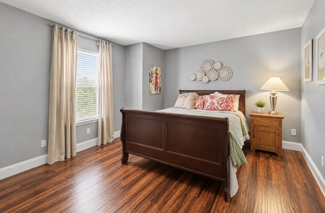 Wood-finish flooring, single window with blinds, light gray walls, and white trim