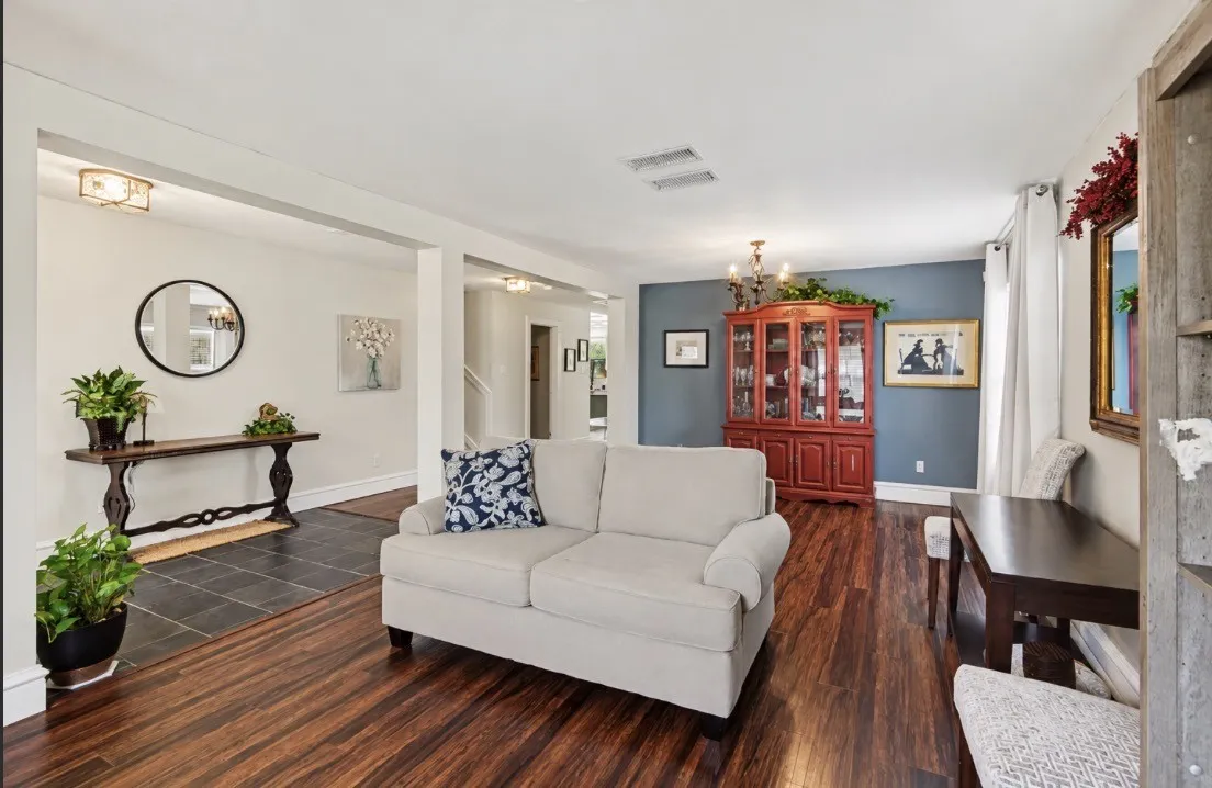 Open concept living area featuring dark wood-finish flooring, a distinct accent wall, and recessed lighting
