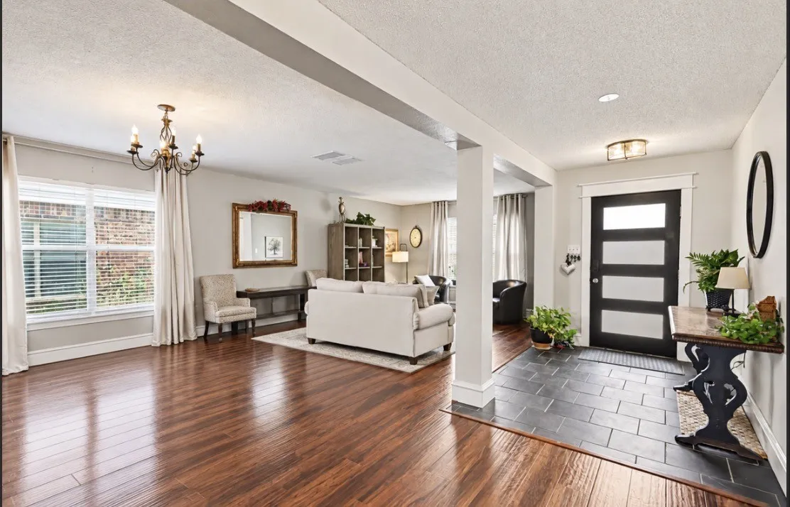 Wood-finish flooring, entry with dark tile, recessed lighting, chandelier, and a black front door with obscured glass panels