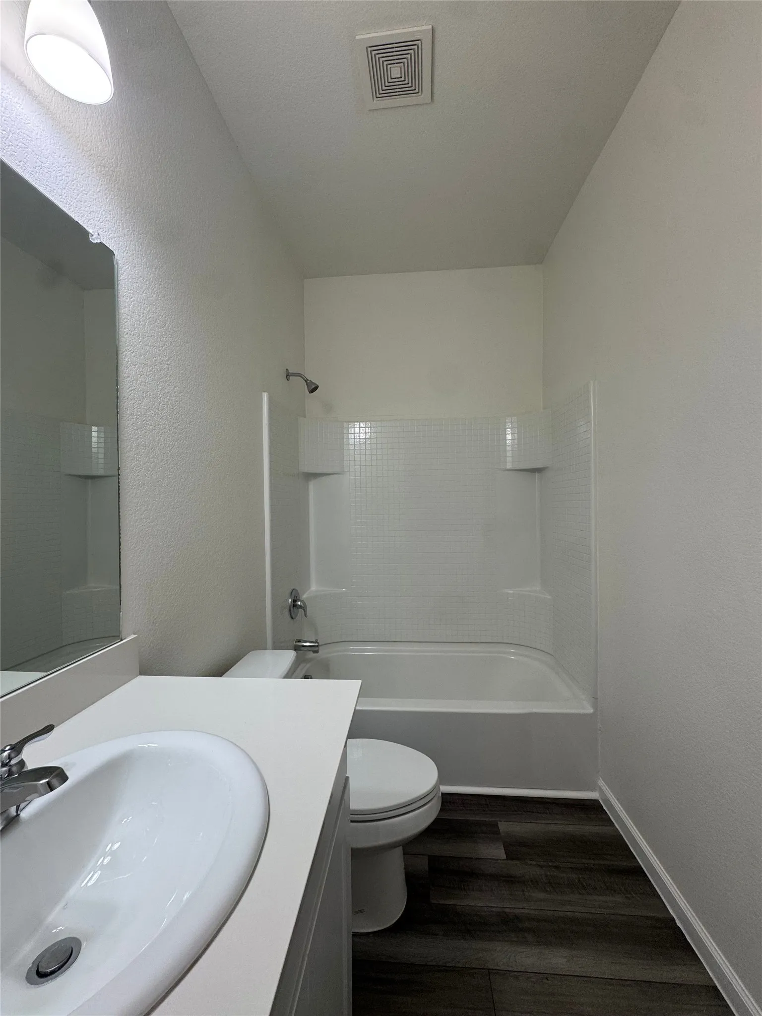 Vanity with an integrated sink, polished chrome faucet, and expansive mirror