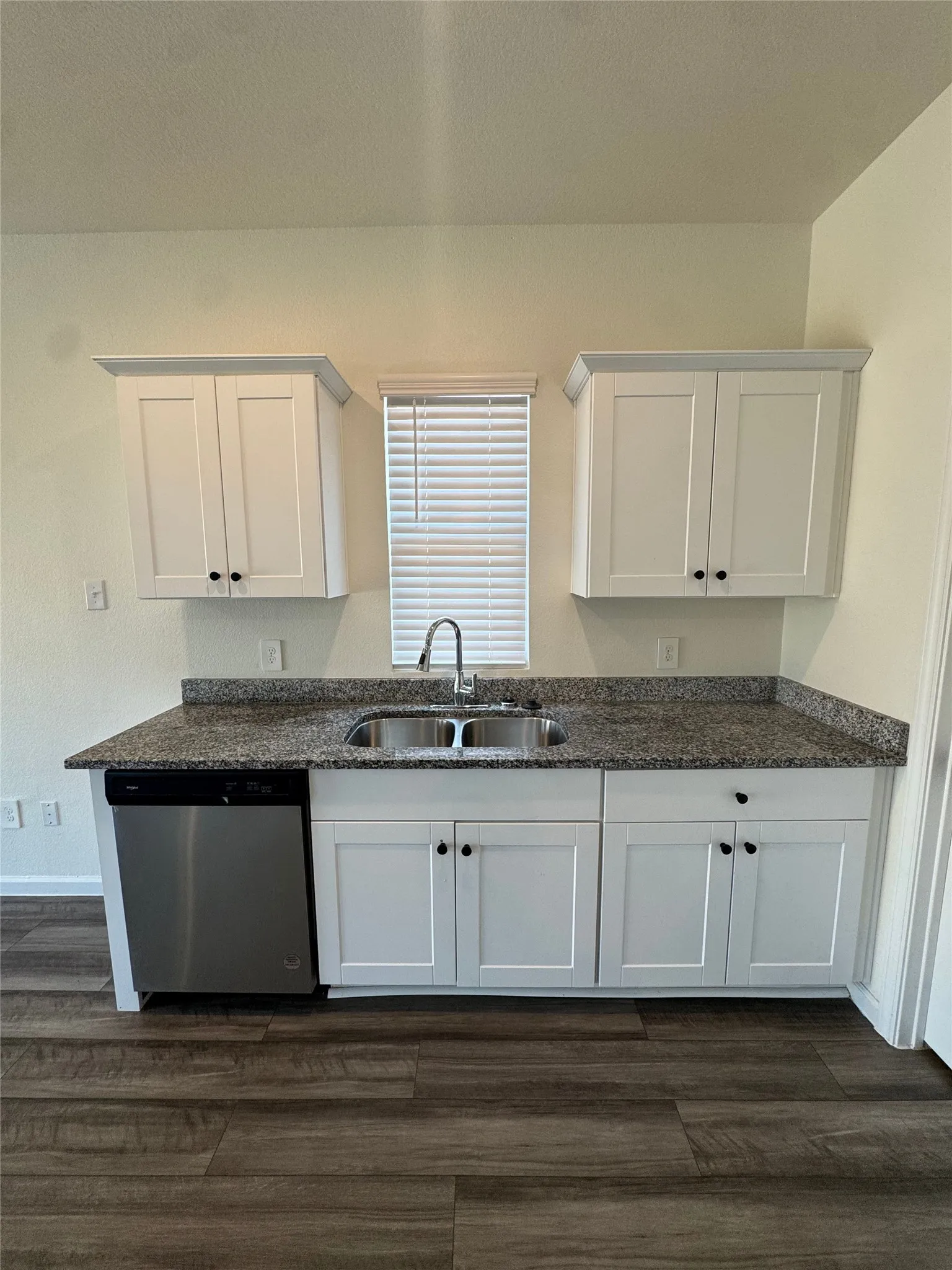 White shaker-style cabinetry, granite-finish countertops, and a stainless steel double basin sink