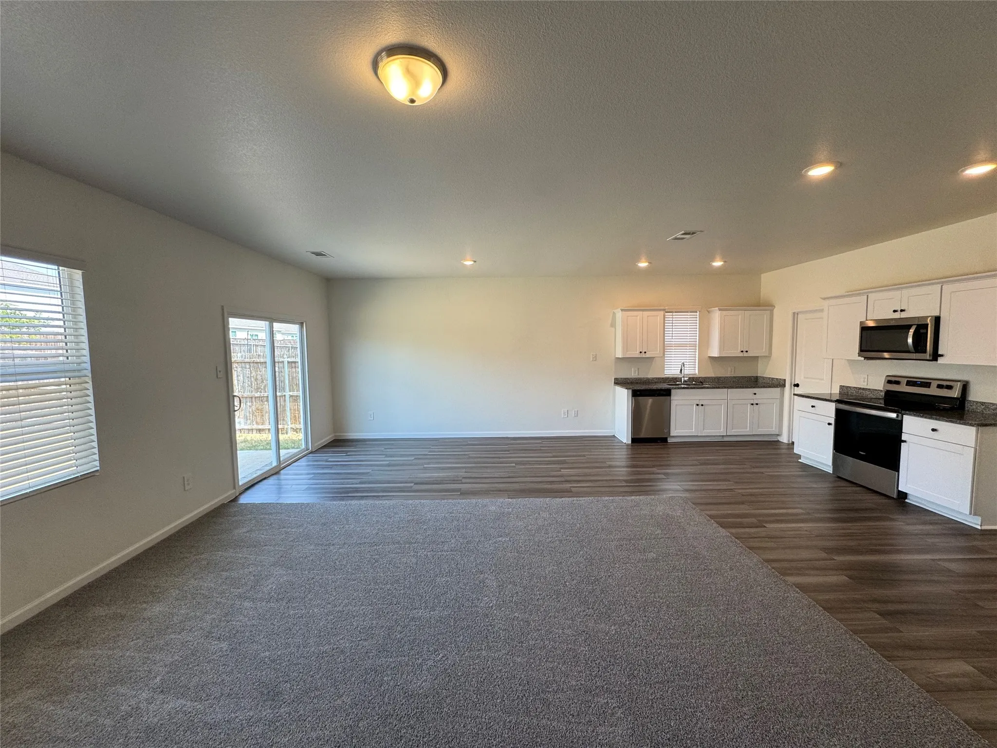 Open-concept living space featuring wood-finish flooring, recessed lighting, and a sliding glass door to the exterior