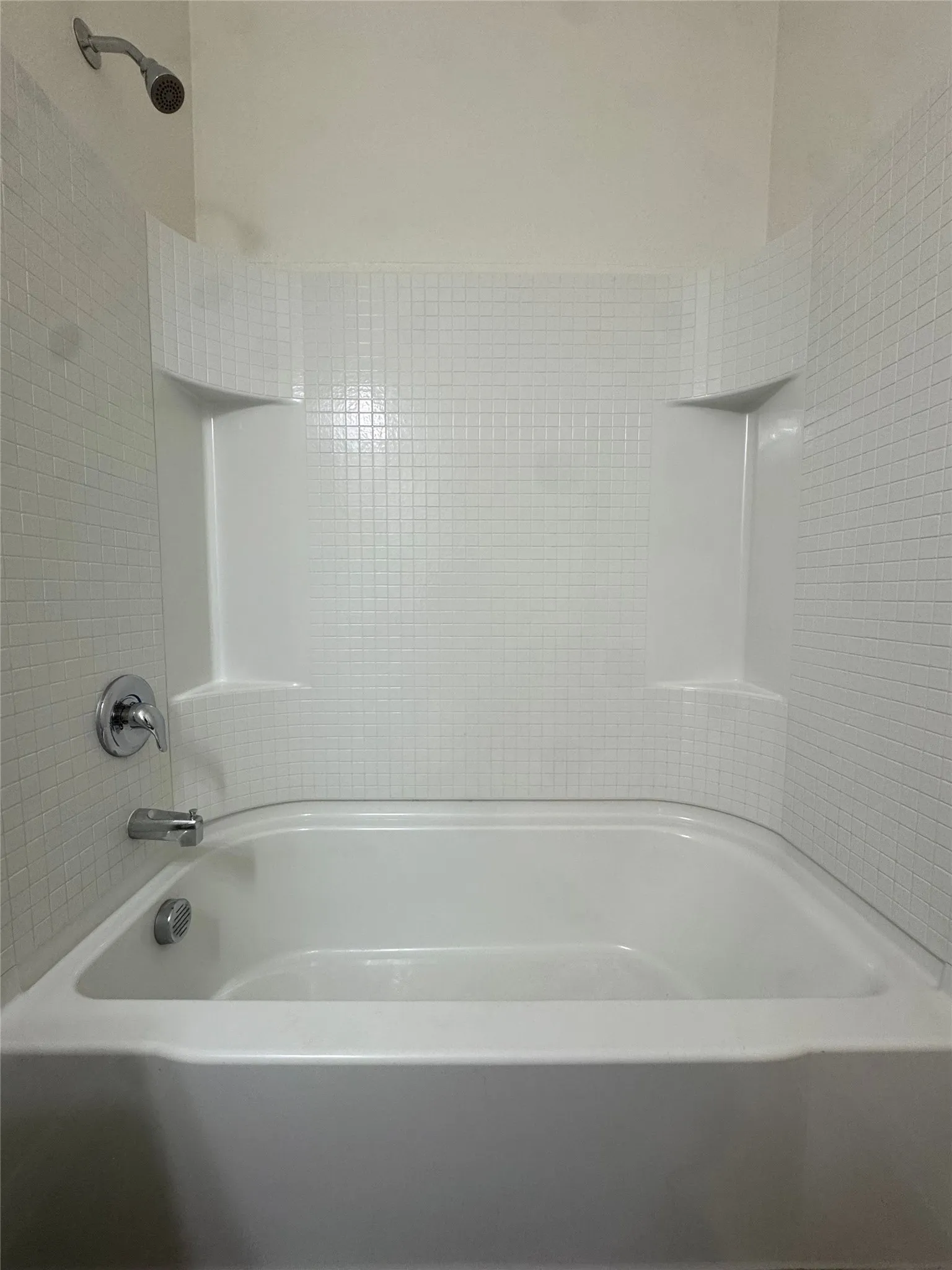 Bathtub with white tile surround and integrated shelving