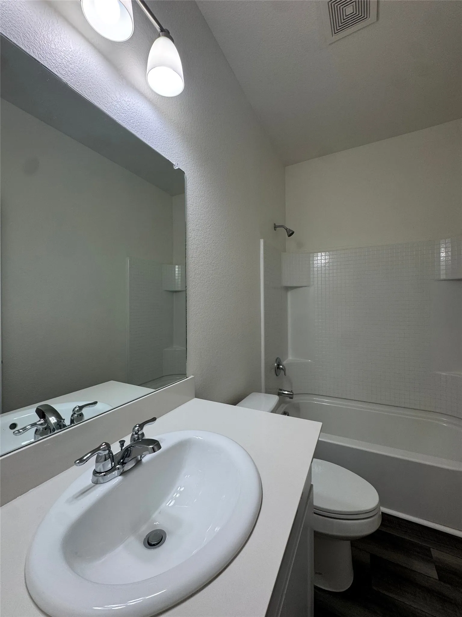 White oval undermount sink with chrome faucet, light-colored countertop, and a full-width mirror