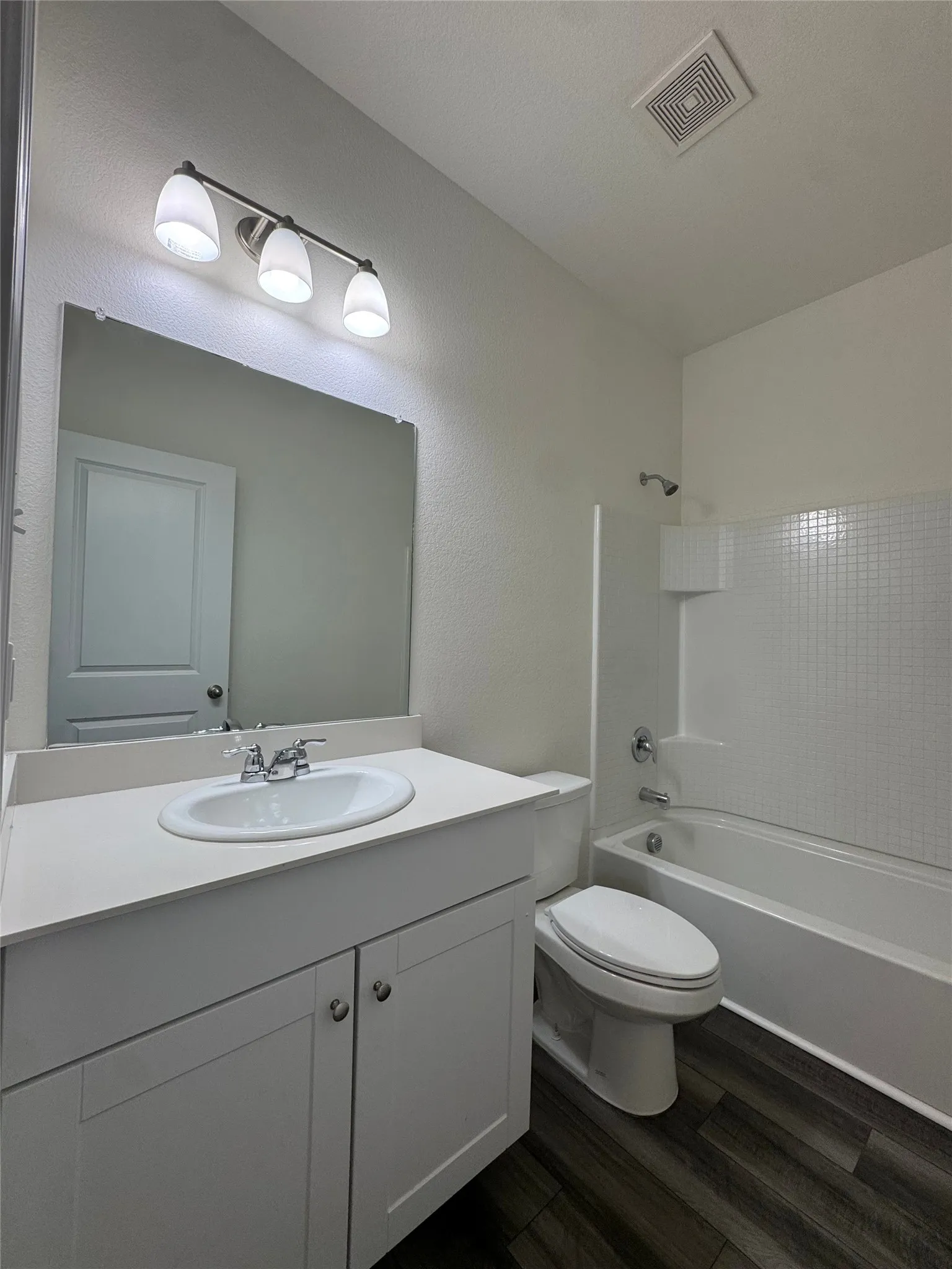 White vanity with integrated sink, chrome faucet, and overhead lighting
