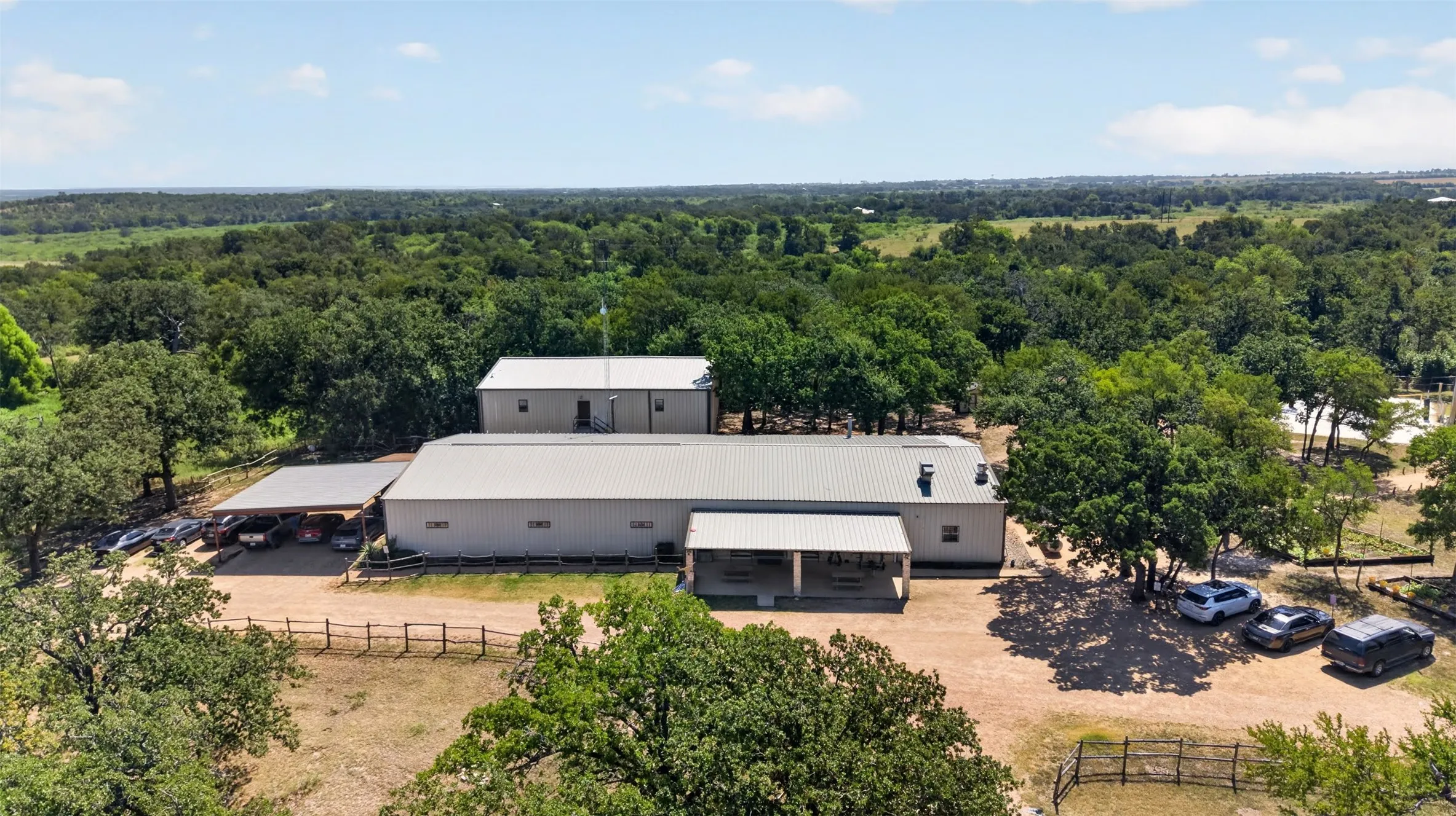 Extensive property featuring multiple outbuildings with metal roofing, a covered carport area, and a large covered patio
