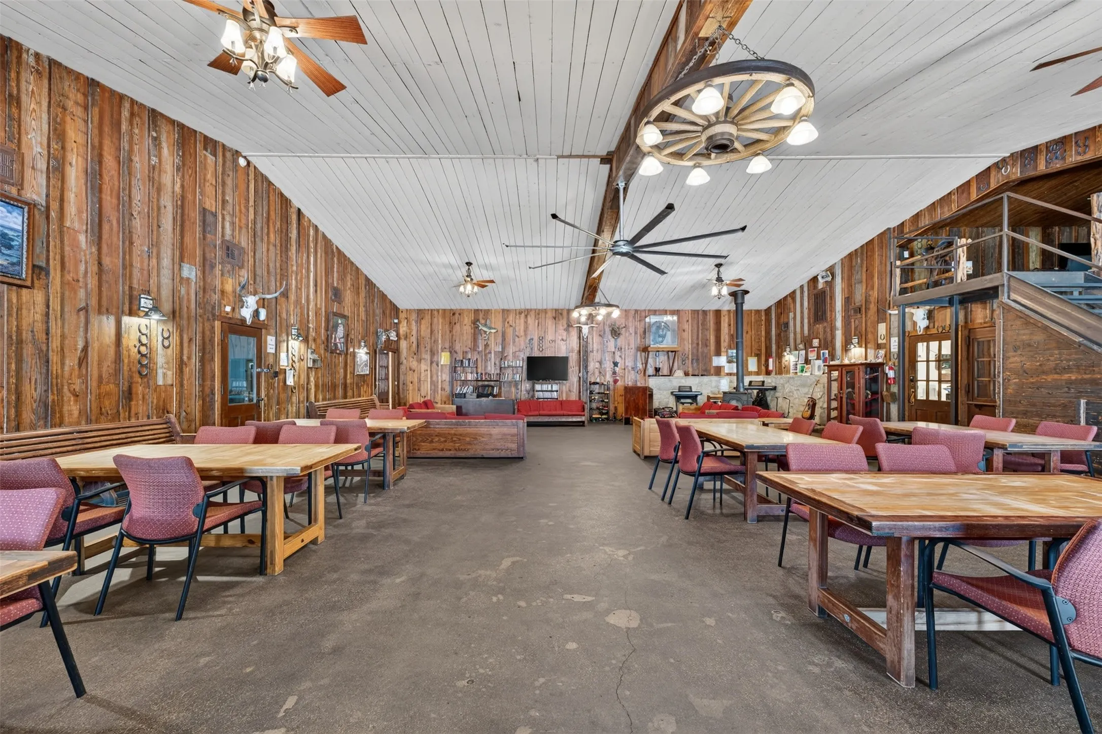 Spacious room featuring wood plank wall paneling, a white plank ceiling, and concrete flooring