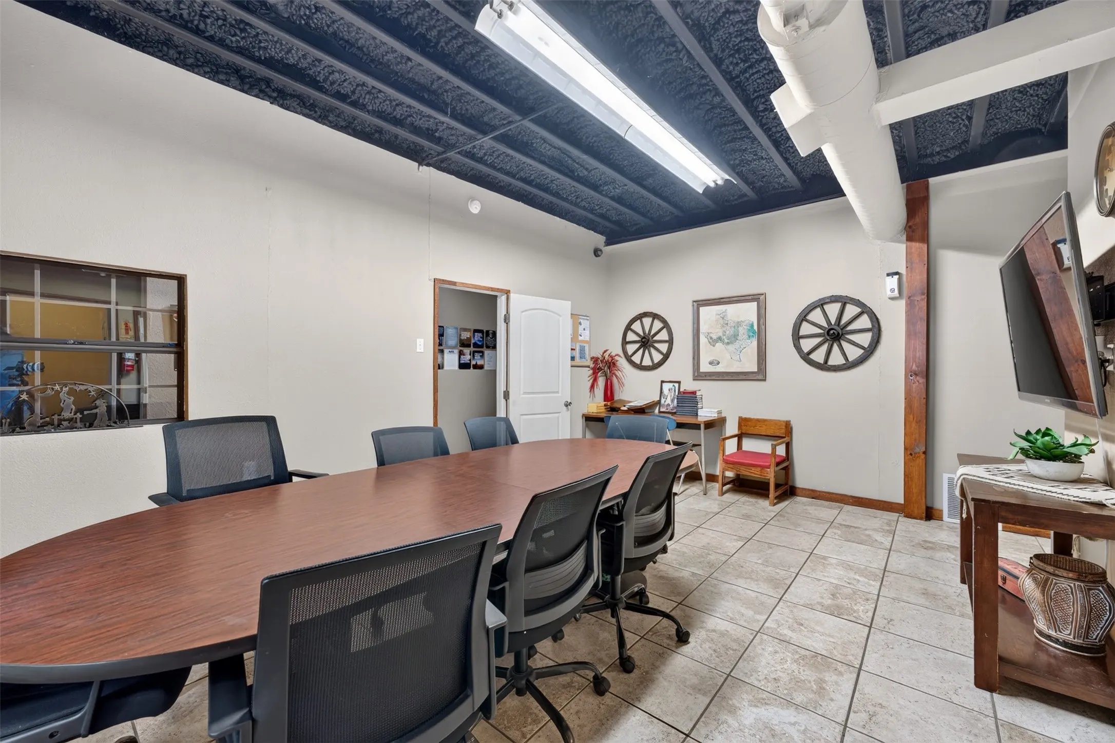 Overhead lighting fixtures, exposed ceiling ductwork, textured ceiling finish, tile flooring, and a window with a multi-pane grid