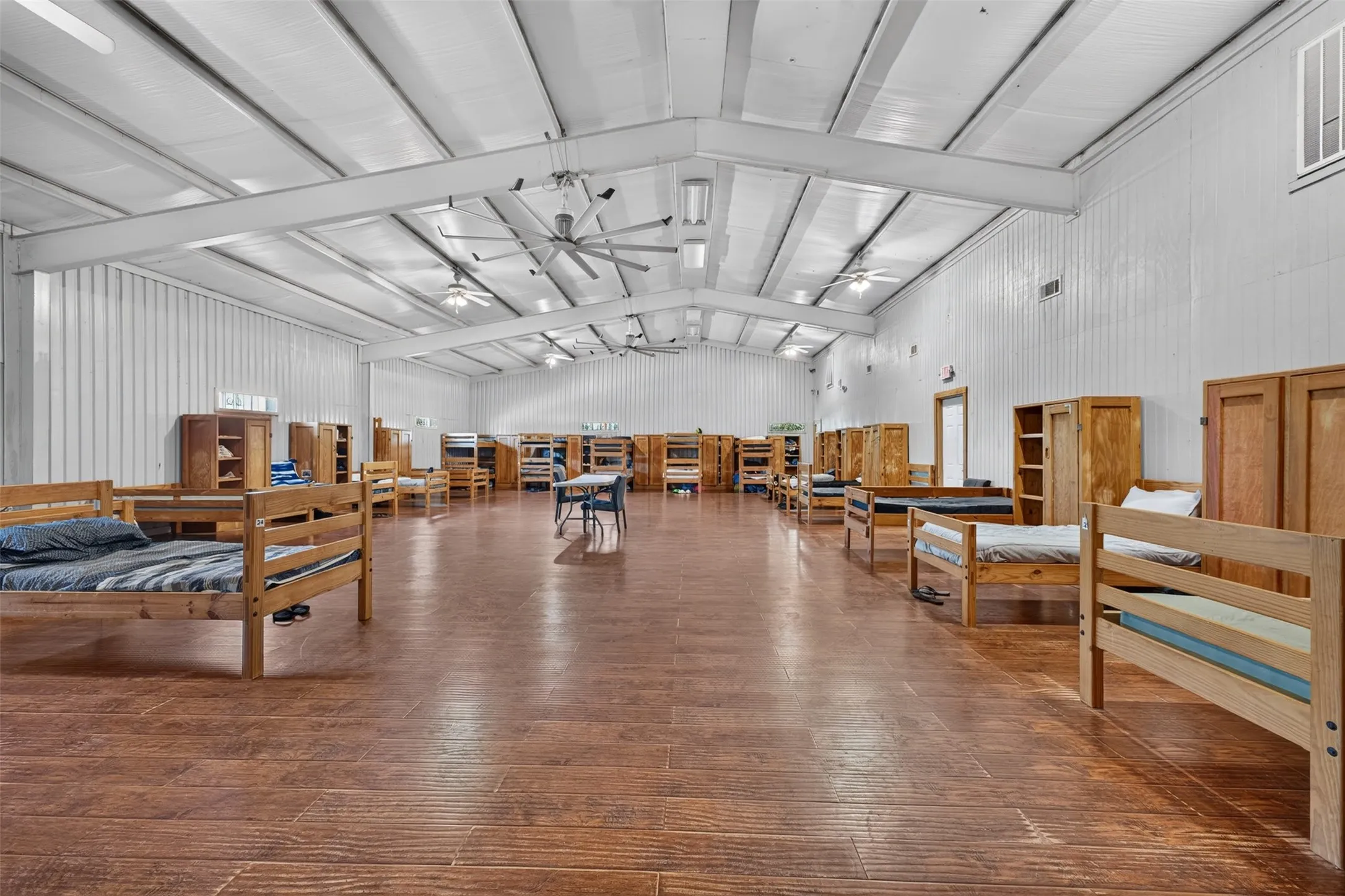 Expansive interior space featuring wood-finish flooring, vaulted ceiling, and multiple ceiling fans