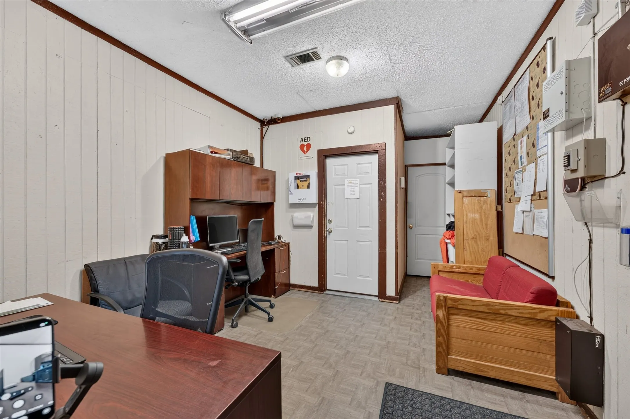 Vertical wood-panel walls with dark trim, dual white paneled doors, and a built-in wood-finish desk with upper cabinetry