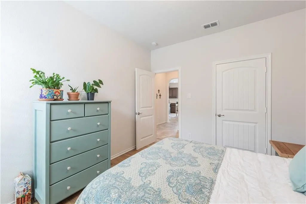 Serene primary bedroom featuring soft neutral walls, wood-finish flooring, and abundant natural light