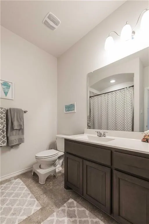 Spa-inspired bathroom featuring a dark wood vanity with dual sink configuration, white quartz countertop, large framed mirror with integrated lighting, and a patterned tile floor
