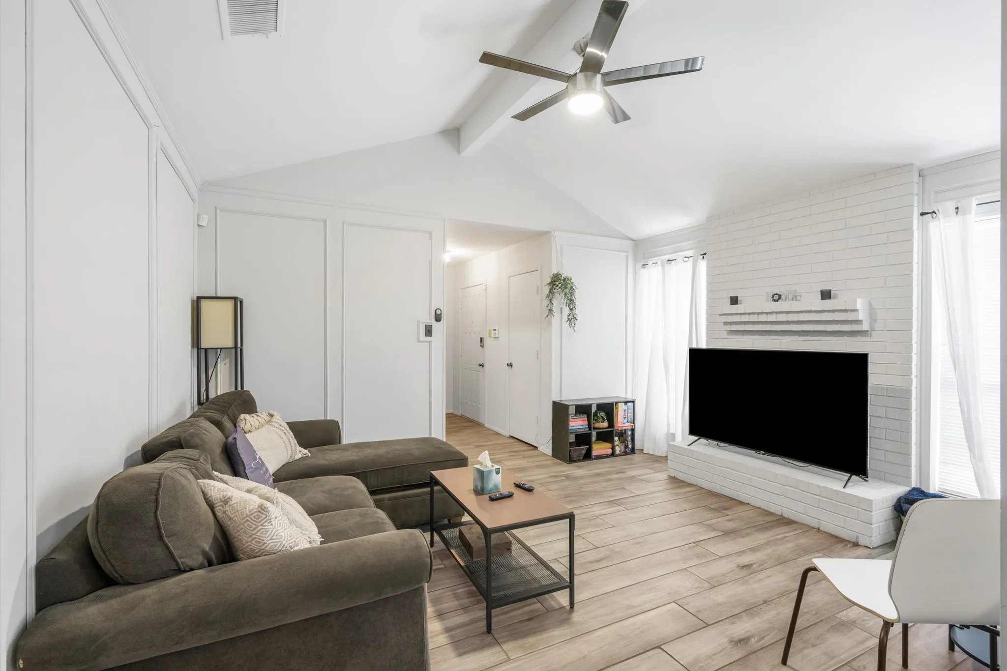 Light and bright living room features a vaulted ceiling with ceiling fan.