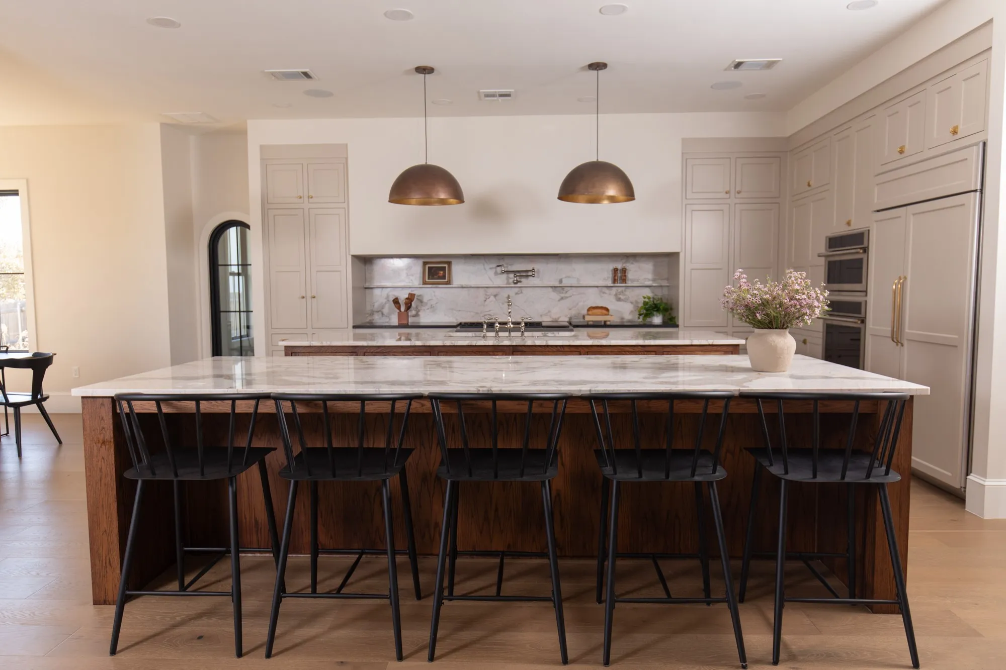 Kitchen featuring light wood-style flooring, light stone countertops, hanging light fixtures, a kitchen bar, and paneled refrigerator