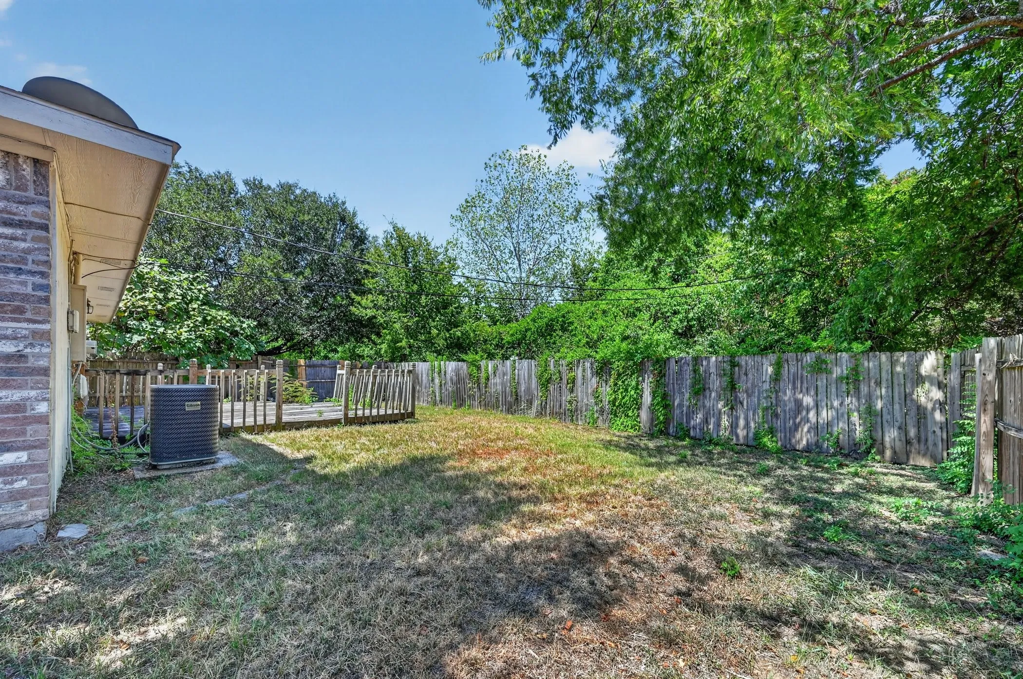 Expansive backyard featuring a wood deck, wood privacy fence, and mature trees