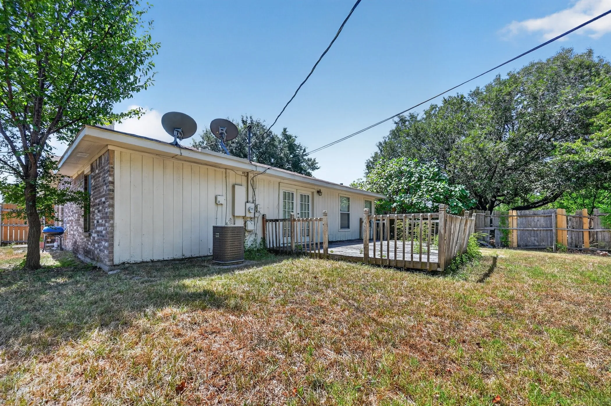 Charming single-story residence featuring a covered front porch with metal railing, metal roof with dual satellite dishes, and horizontal siding exterior