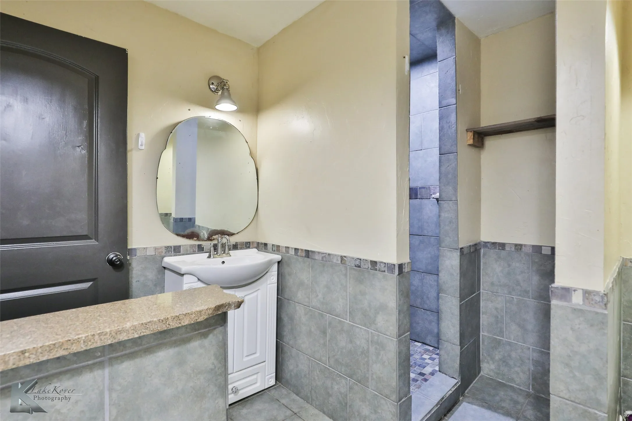 Contemporary bathroom featuring a curved vanity mirror with integrated lighting, vessel sink, and quartz countertop