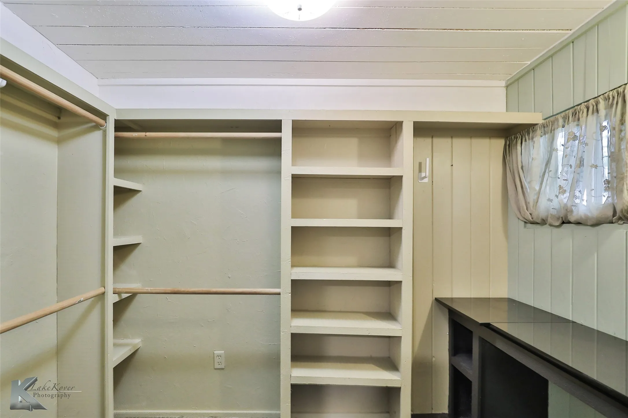 Built-in shelving, hanging rods, paneled walls, and a fixed counter
