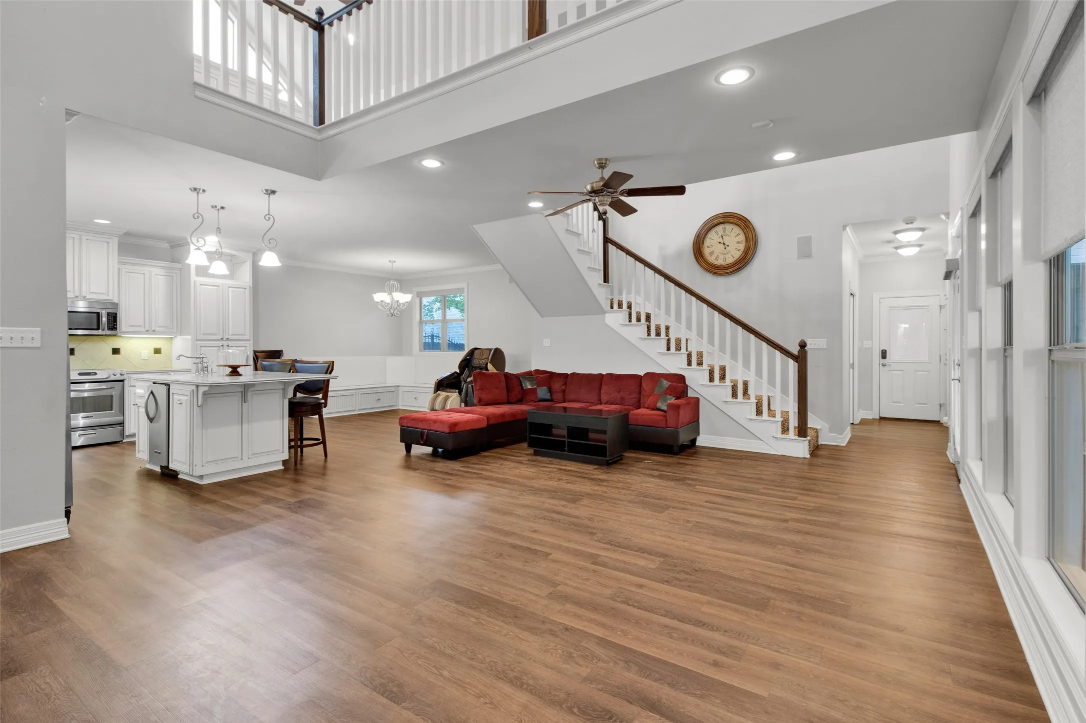 Expansive main living area featuring wood-finish flooring, a two-story ceiling, and abundant natural light from multiple windows